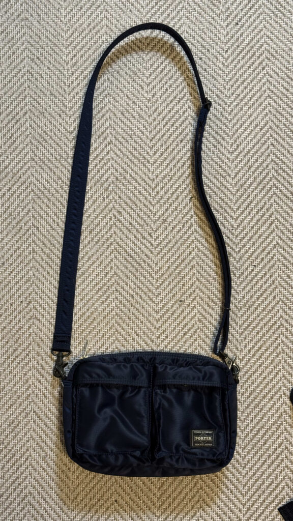 Navy blue Porter shoulder bag placed flat on a herringbone pattern rug