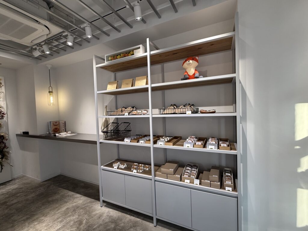 Baked goods and a fox plush toy displayed on white shelves in a shop
