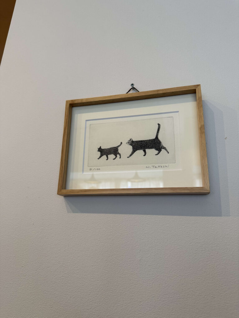 Framed print of two black cats hanging on a white wall