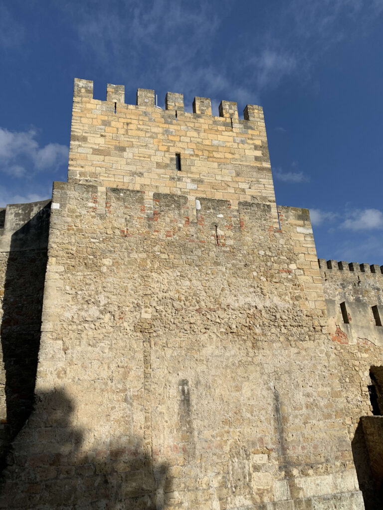 A towering stone fortress tower with weathered walls against a blue sky