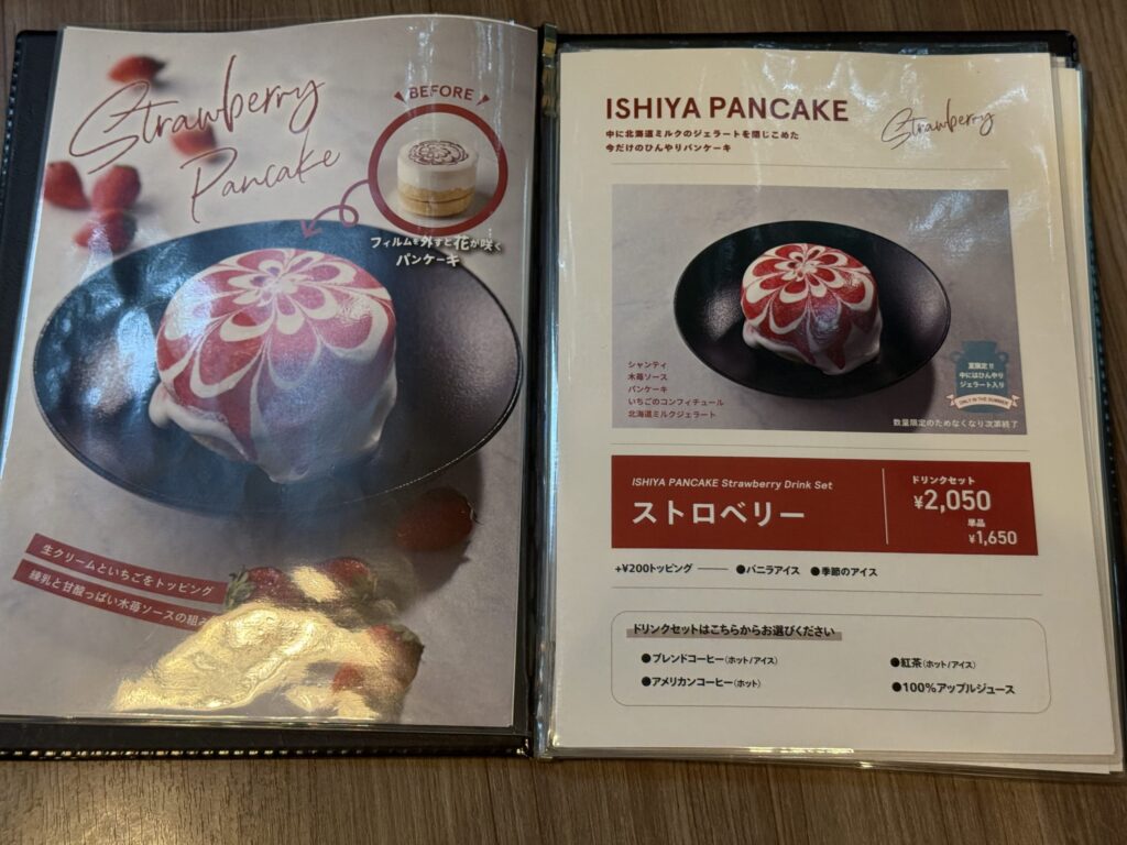 ISHIYA PANCAKE(イシヤパンケーキ)ストロベリーのメニュー表。フィルムを外すと花のような模様が広がるビフォーアフターの写真と、ドリンクセット2,050円の価格が掲載されている。