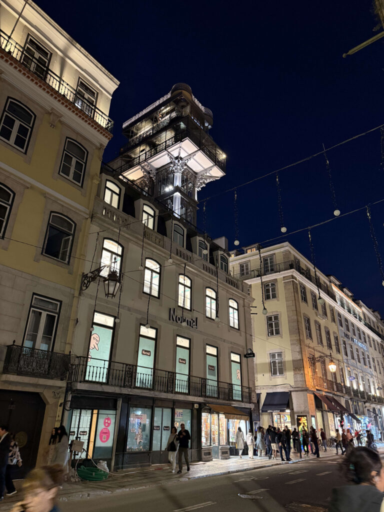 Night view of the illuminated Santa Justa Lift in Lisbon with the Normal store building on the left