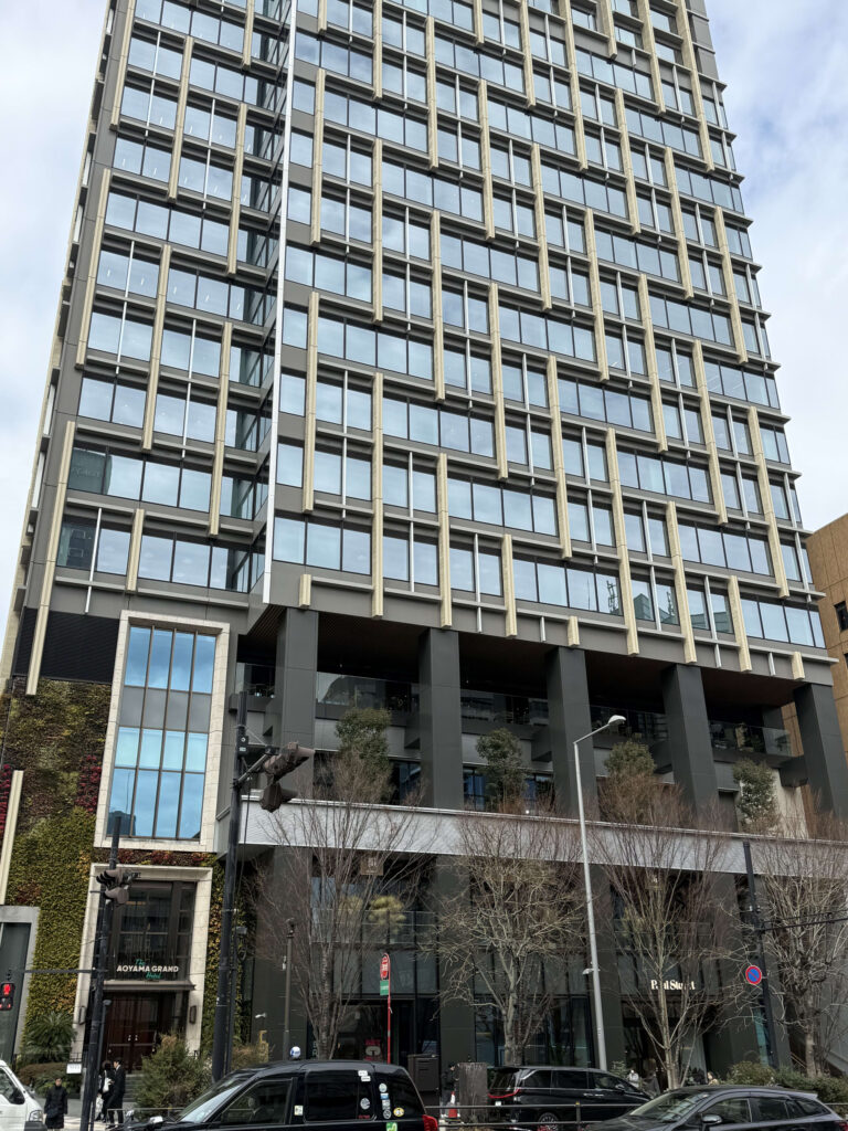 Exterior of The Aoyama Grand Hotel featuring a geometric grid facade and beige louvers