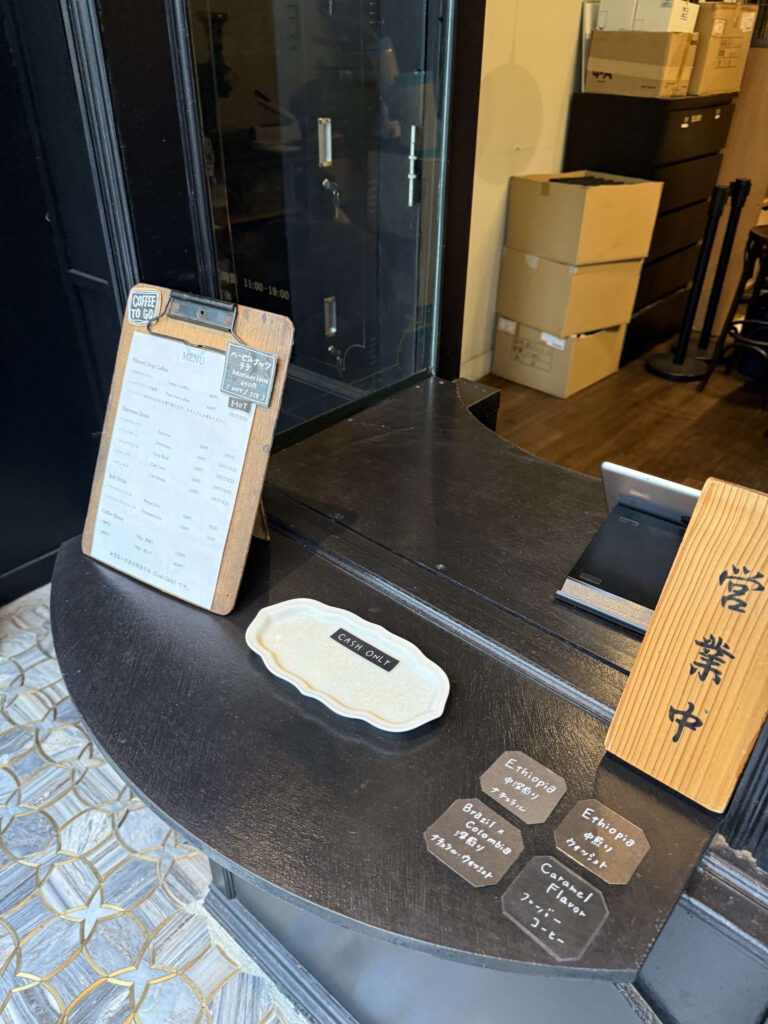 Coffee shop counter with menu clipboard, cash tray, and open sign
