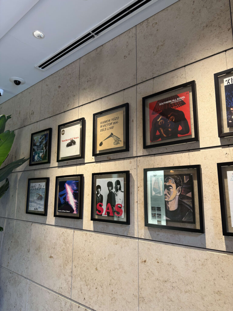 Framed Southern All Stars record jackets and artwork displayed on a textured stone wall