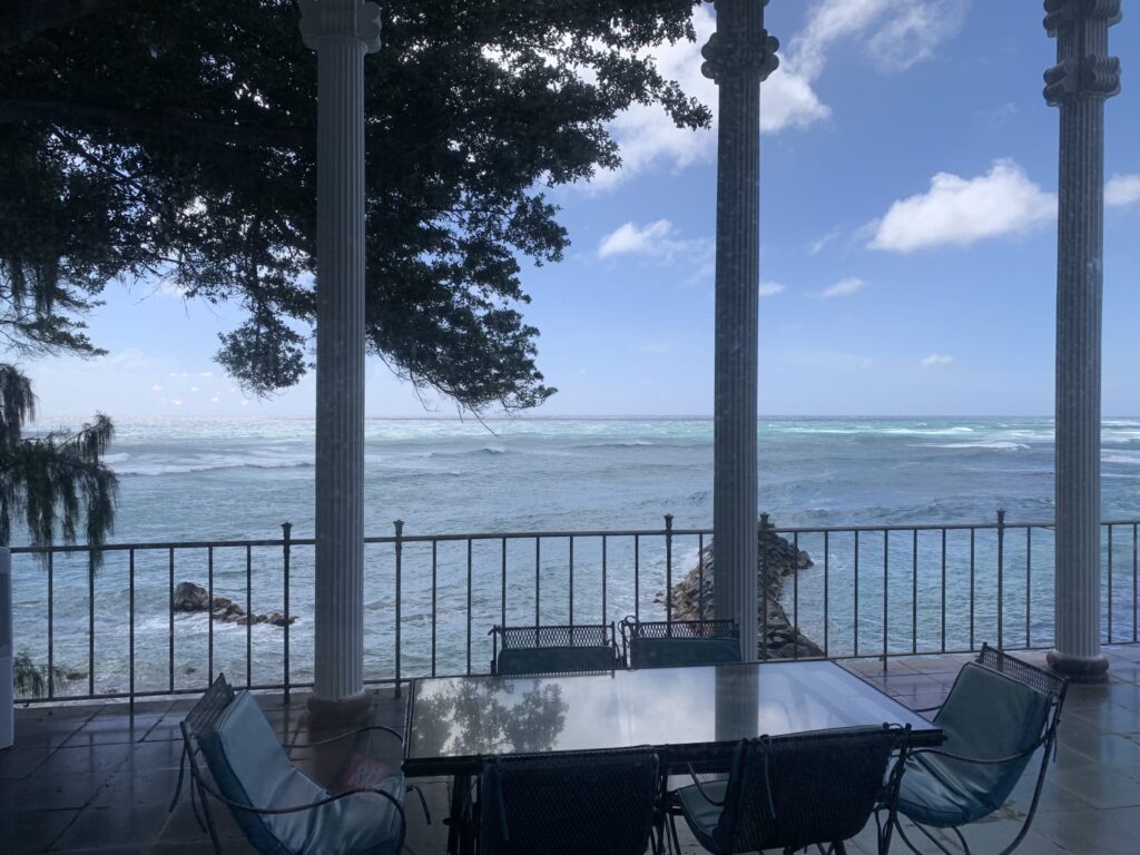 海を一望する柱のあるテラスとガラスのダイニングテーブル