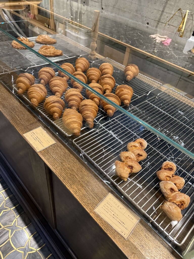 夕方のパン屋のショーケースにずらりと並ぶクロワッサンと少数のベーコンエピ