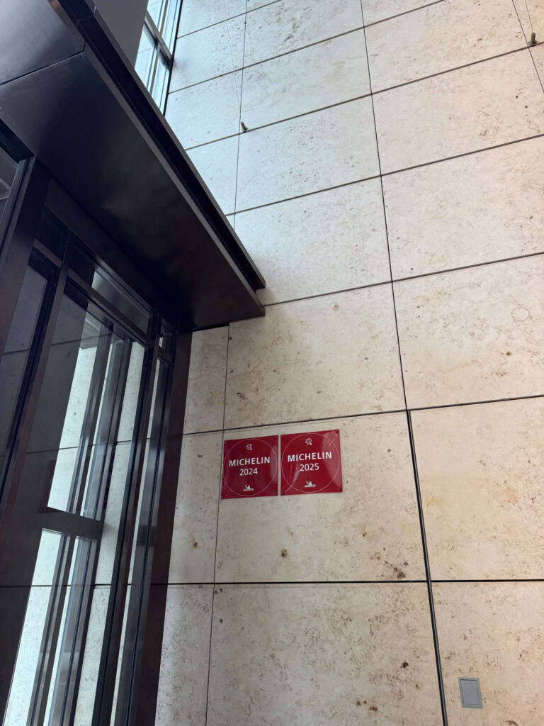Red Michelin 2024 and 2025 stickers affixed to a stone wall near a building entrance