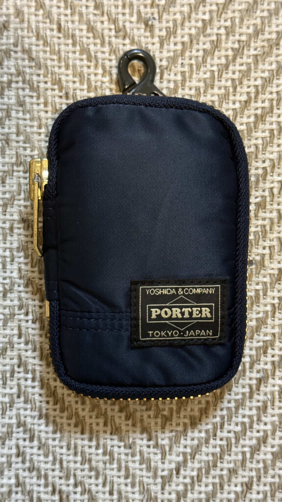 Navy blue Porter Yoshida & Co. Tanker series key case placed on a woven fabric background
