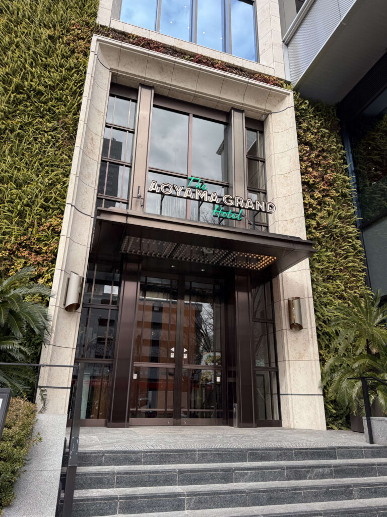 緑の壁面緑化に囲まれた「The AOYAMA GRAND Hotel」の正面エントランスと石造りの階段