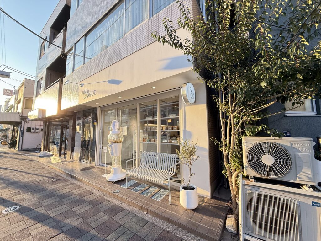 夕日が差し込む清澄白河の商店街にある、白い外壁とベンチが特徴的なおしゃれな店舗の外観