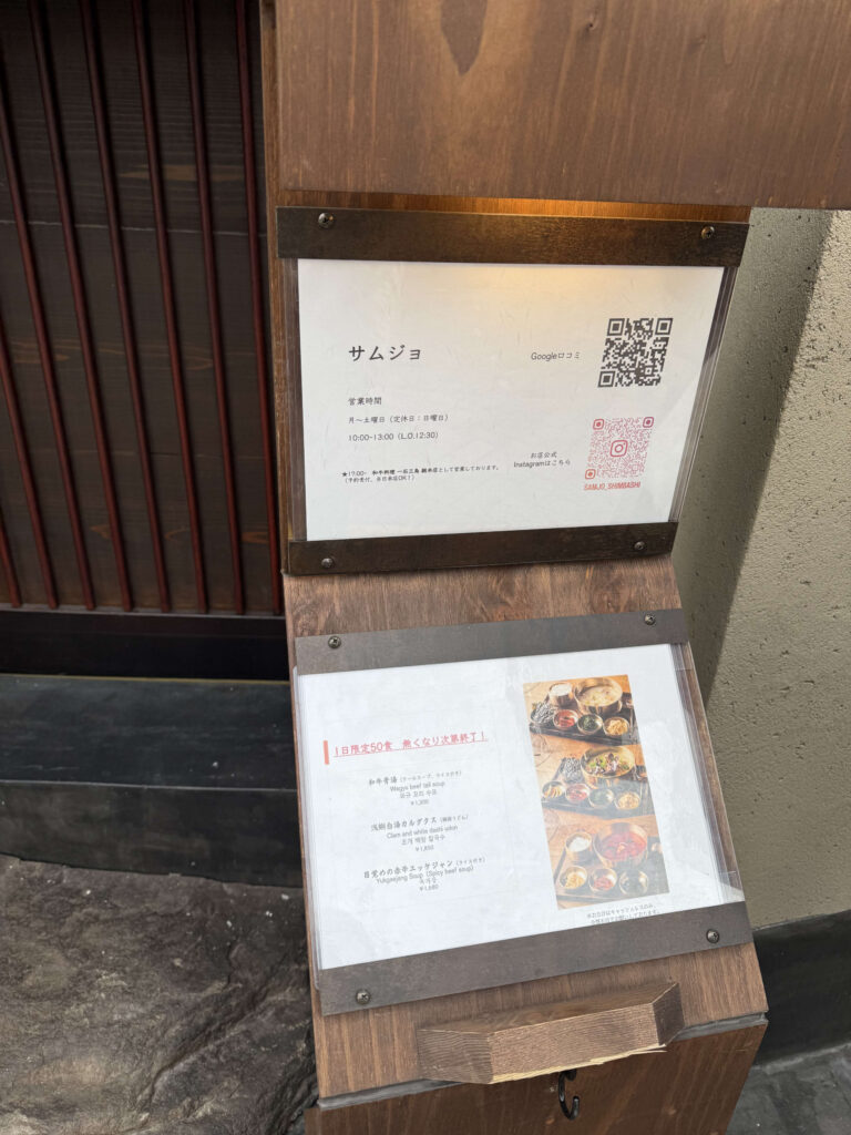 Wooden entrance sign for the restaurant Samjo in Nishi-Shimbashi, displaying business hours, QR codes, and lunch menu photos including Wagyu Beef Tail Soup