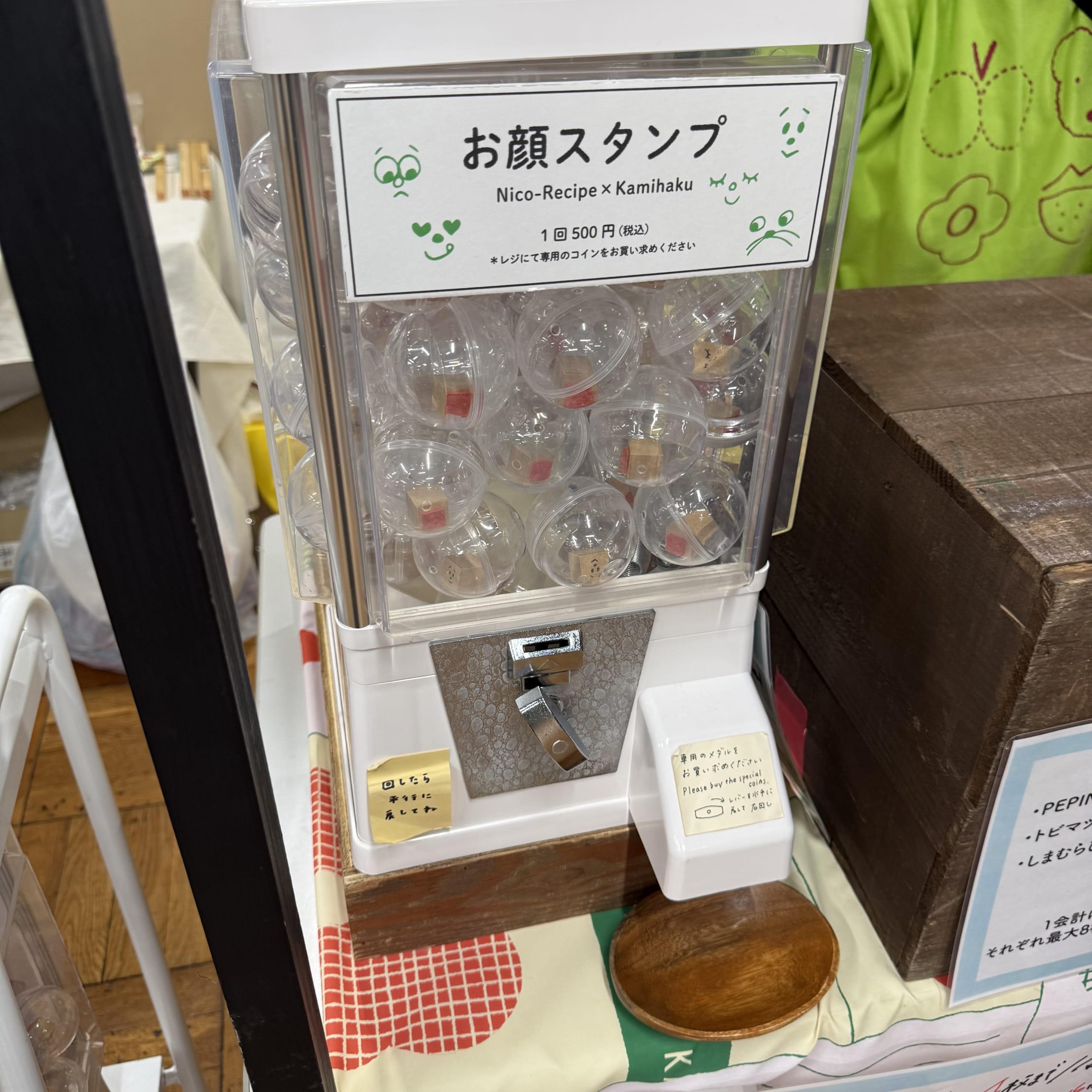 「お顔スタンプ」のガチャマシン。透明カプセルが入っている。