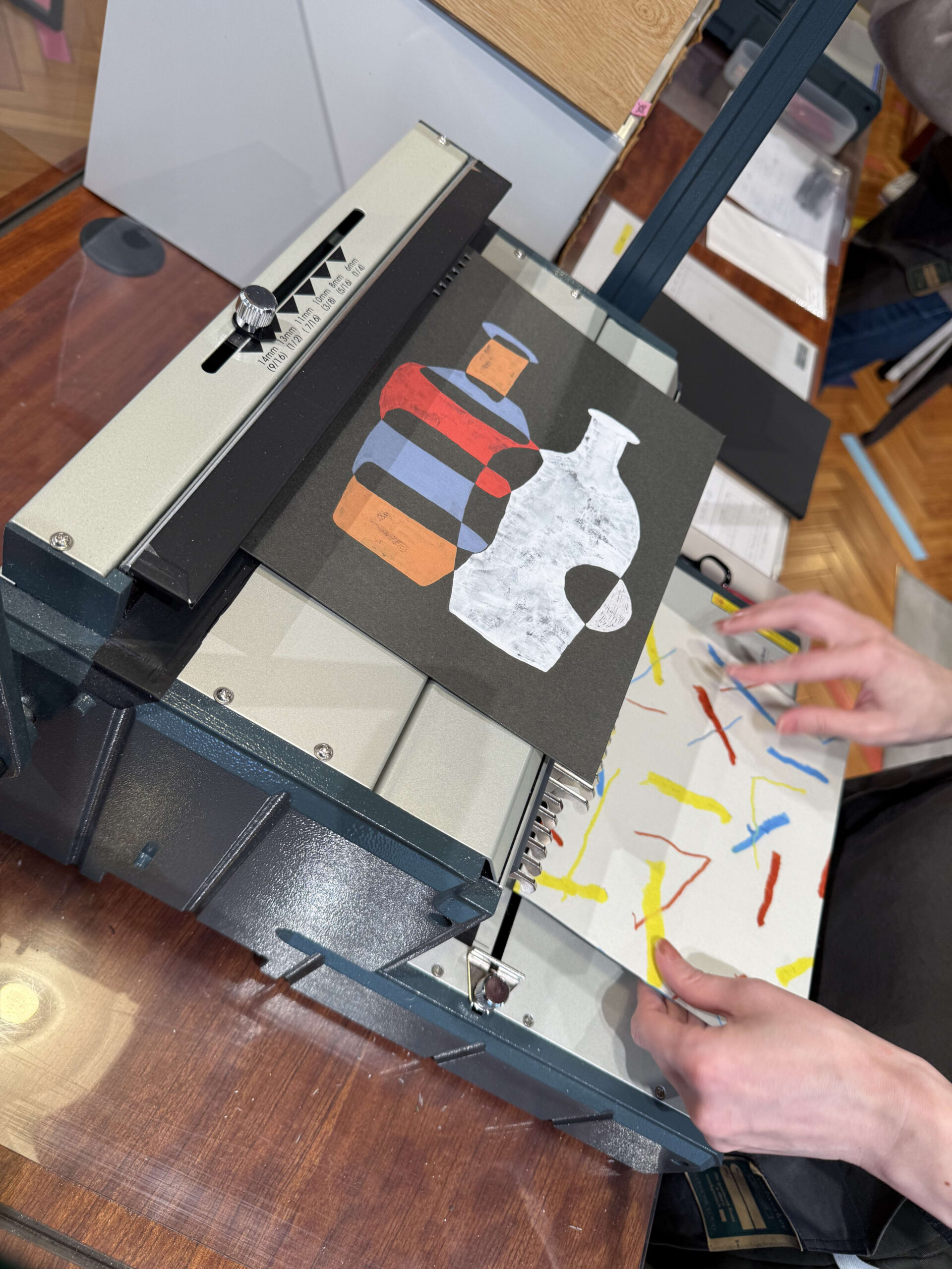 Hands setting printed papers in a metal binder.