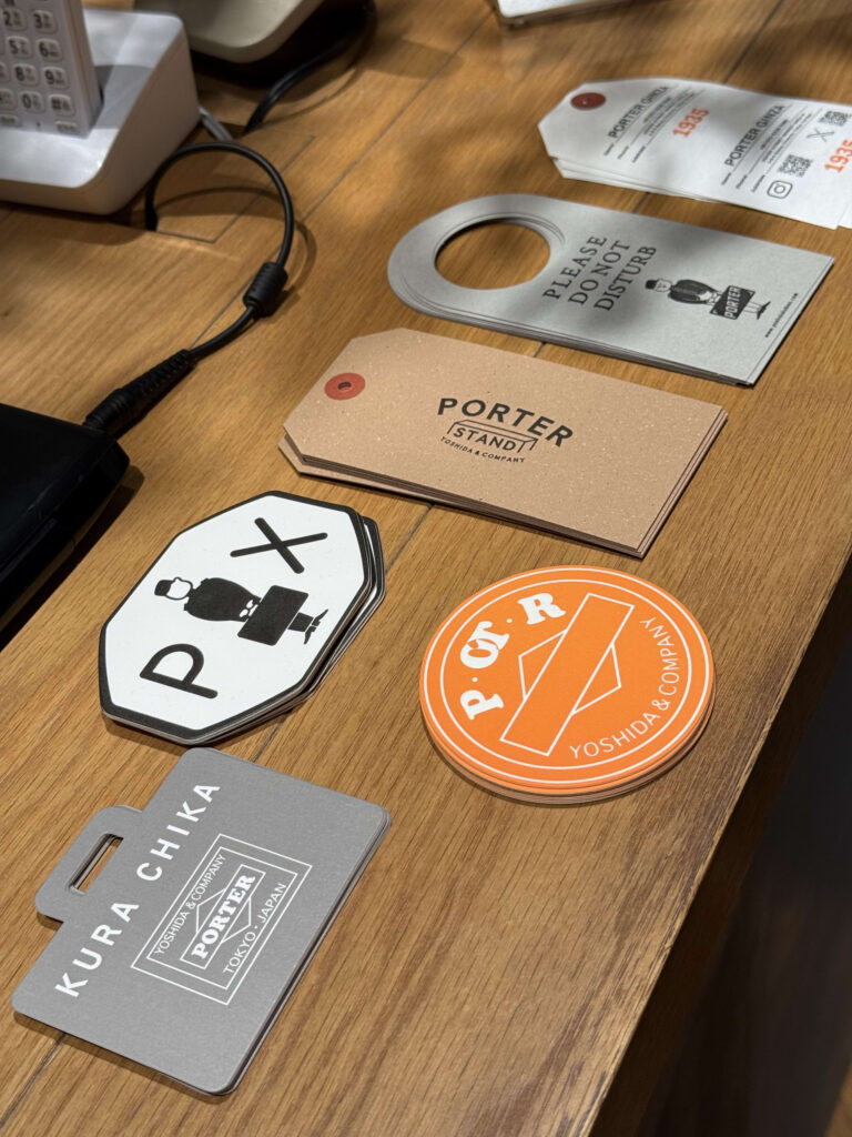 A collection of Porter brand paper tags and stickers featuring logos like PORTER STAND, PX, and P.O.T.R arranged on a wooden counter