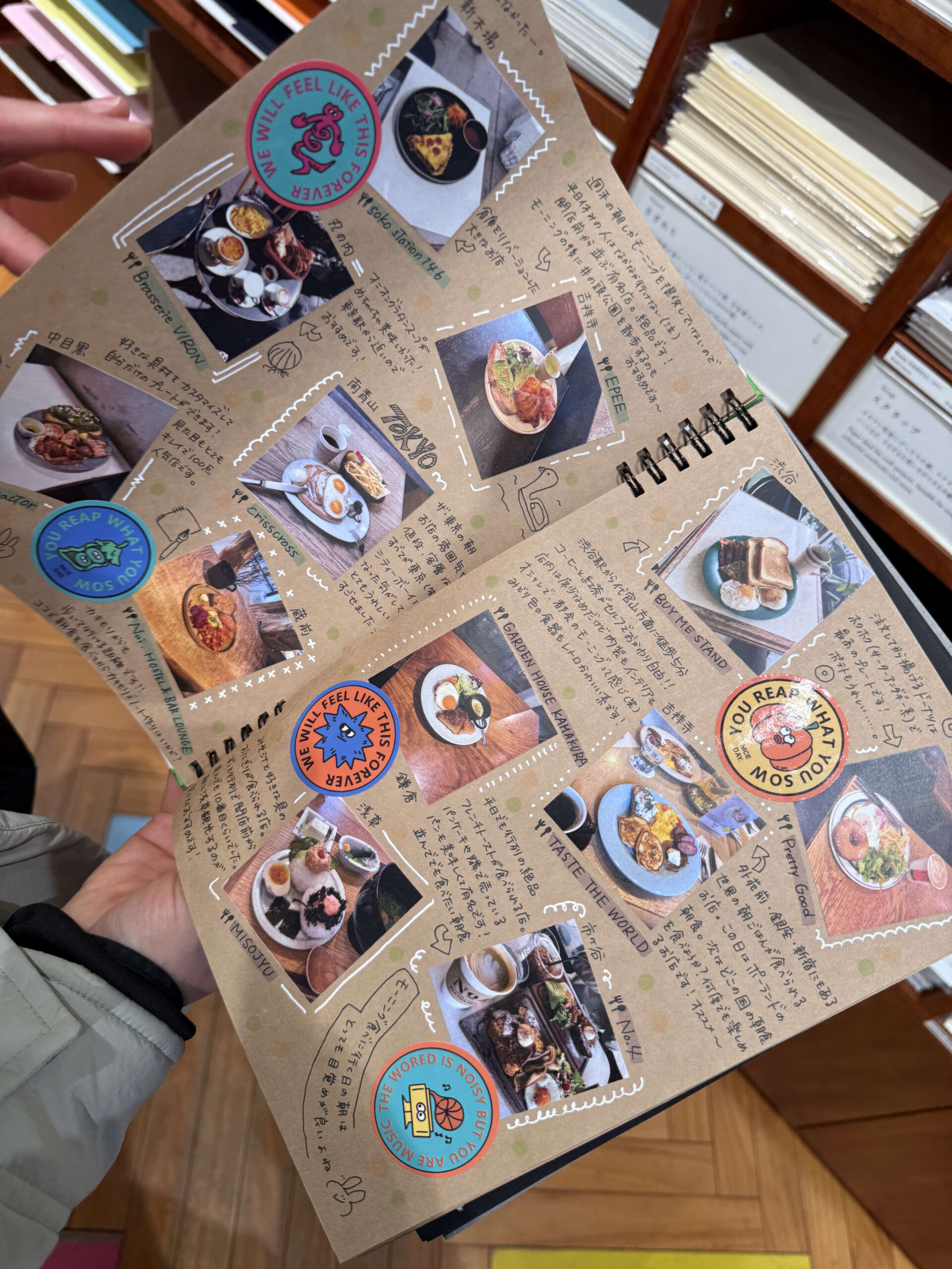 Hands opening a handmade breakfast scrapbook with photos and notes.