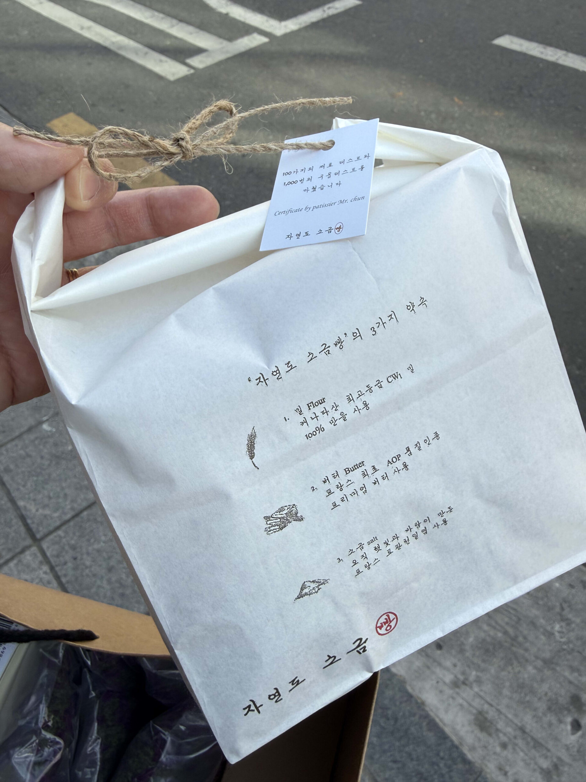 Hand holding a Jayeondo Salt Bread paper bag.