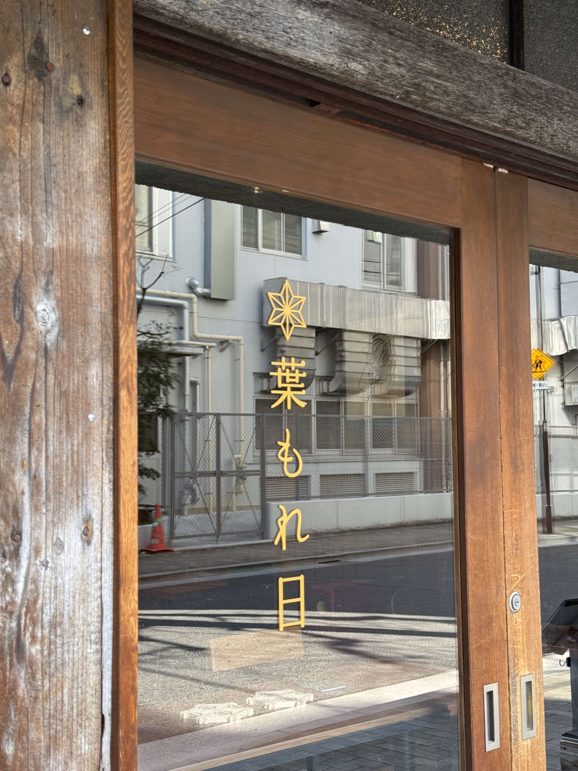 金色の店名ロゴが記された木枠のガラス戸。