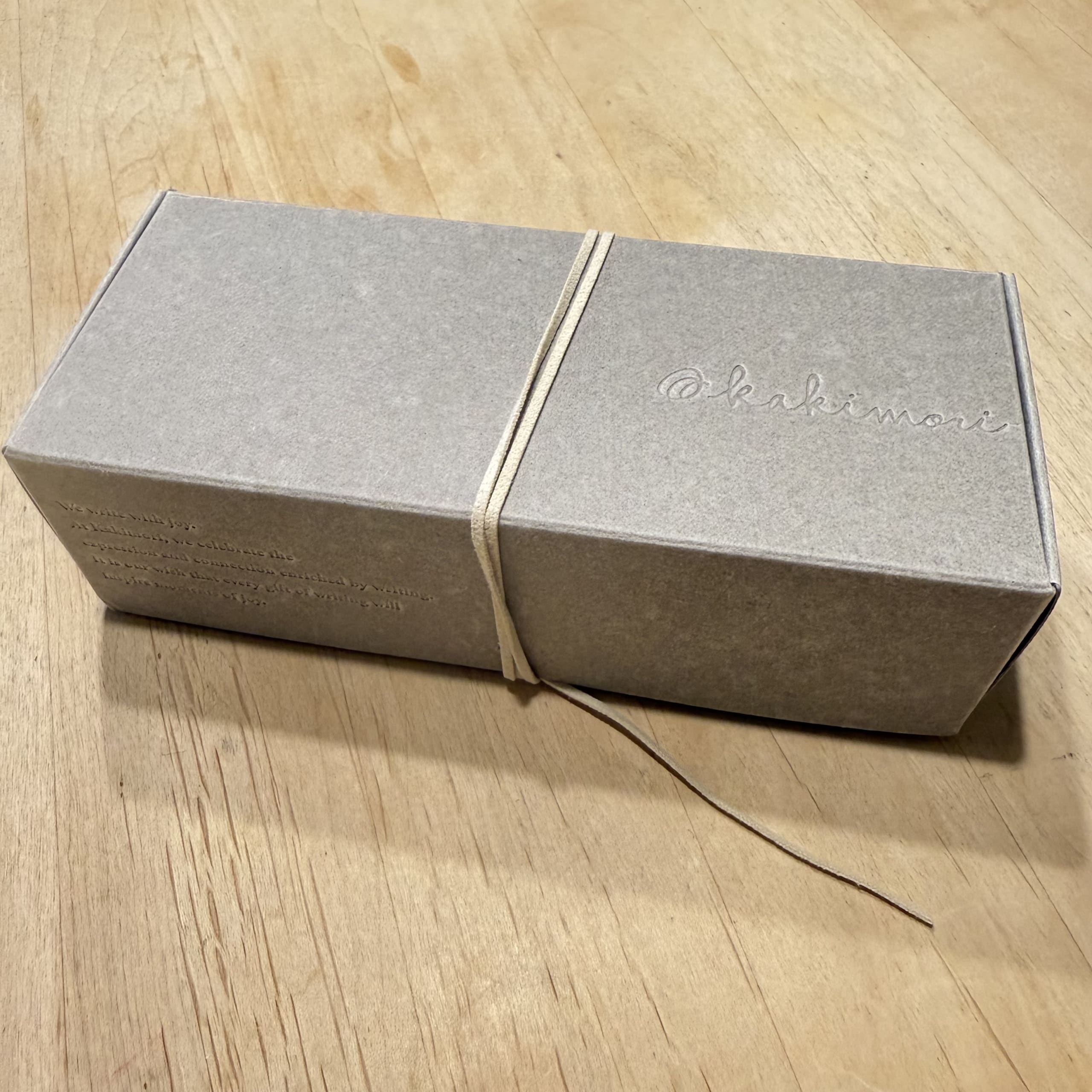 木製の机に置かれたカキモリのグレーの箱。