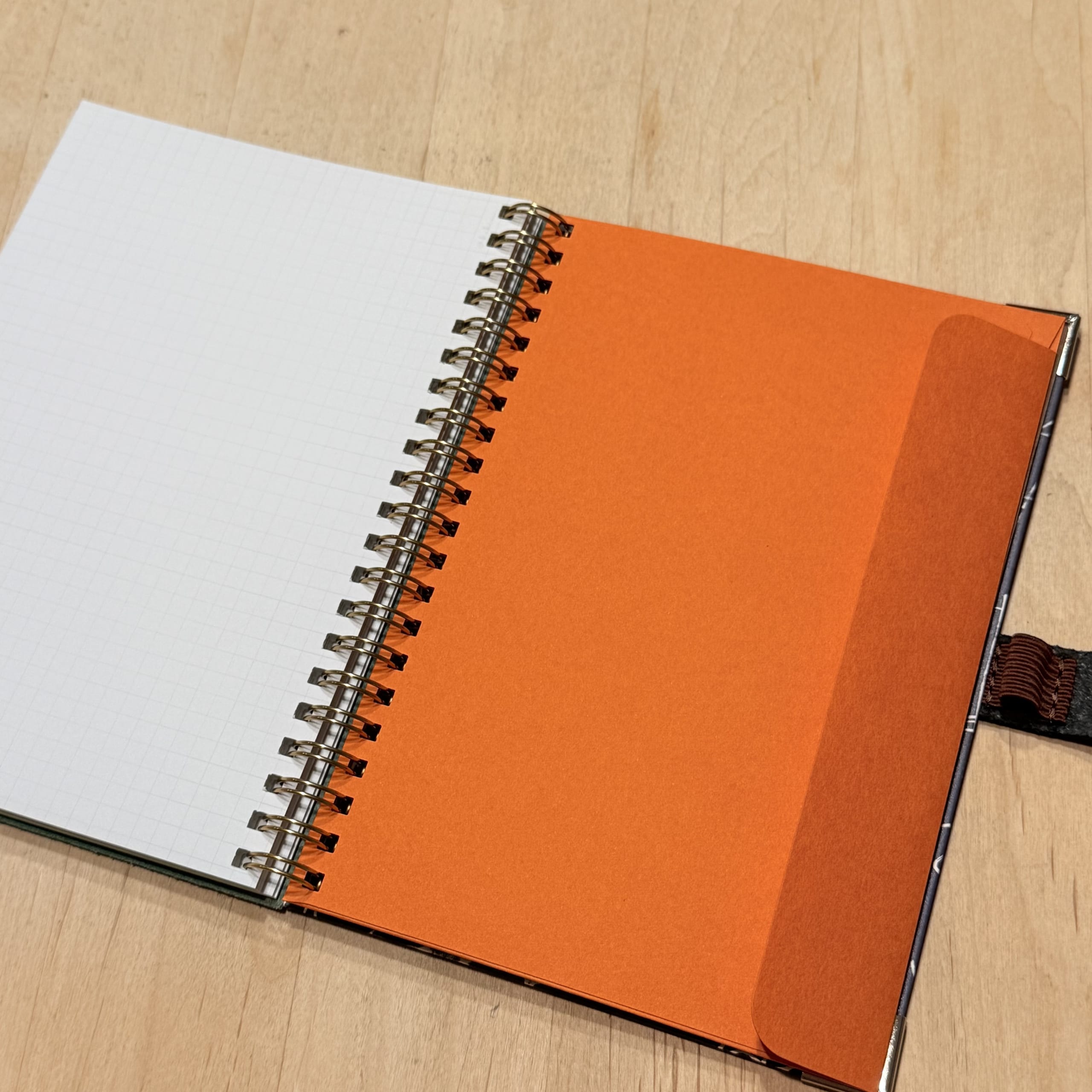 Open notebook with grid paper and orange pocket.