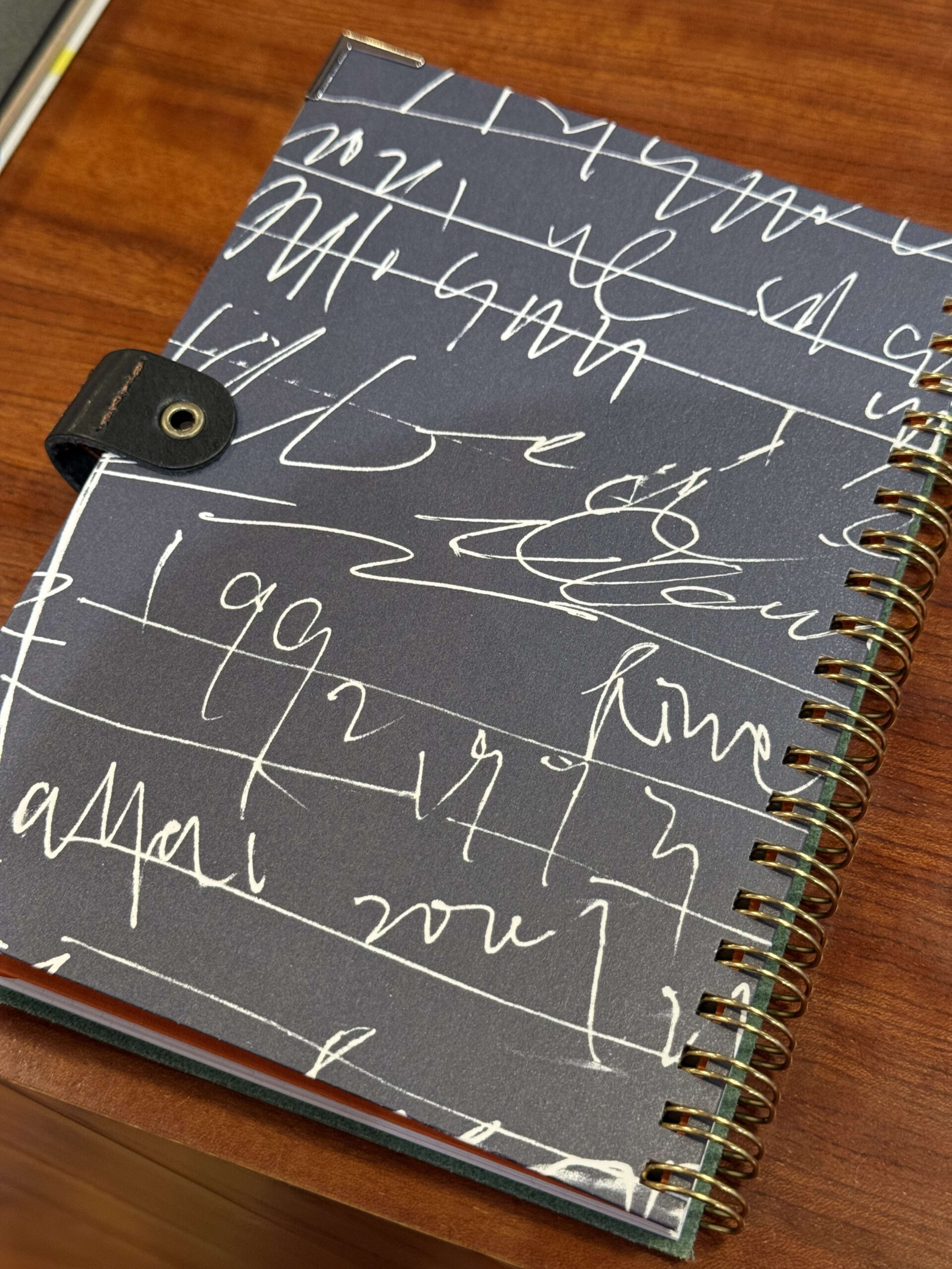 Black spiral notebook with white abstract lines.