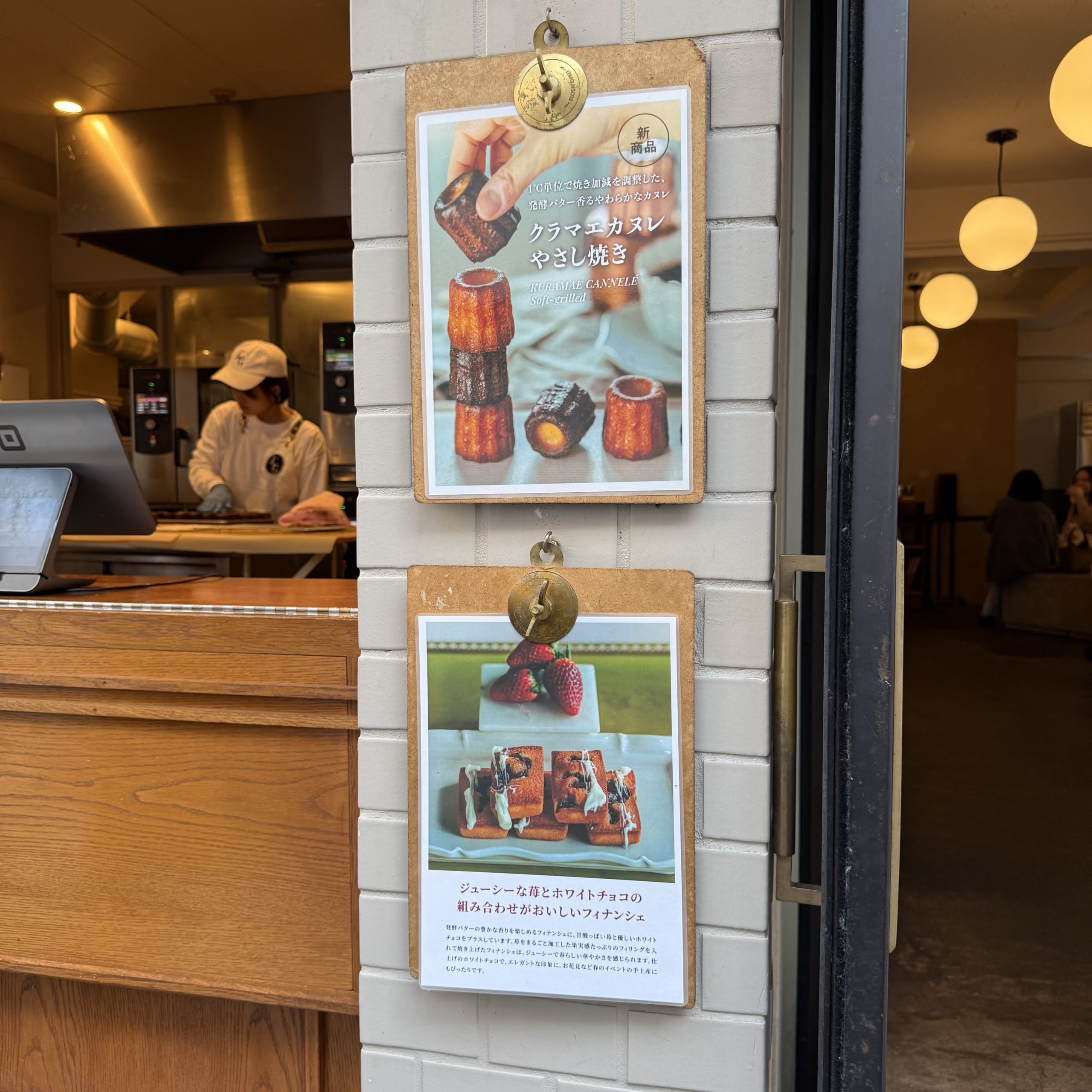 Kuramae Cannele entrance with menus on a brick wall and an open kitchen.