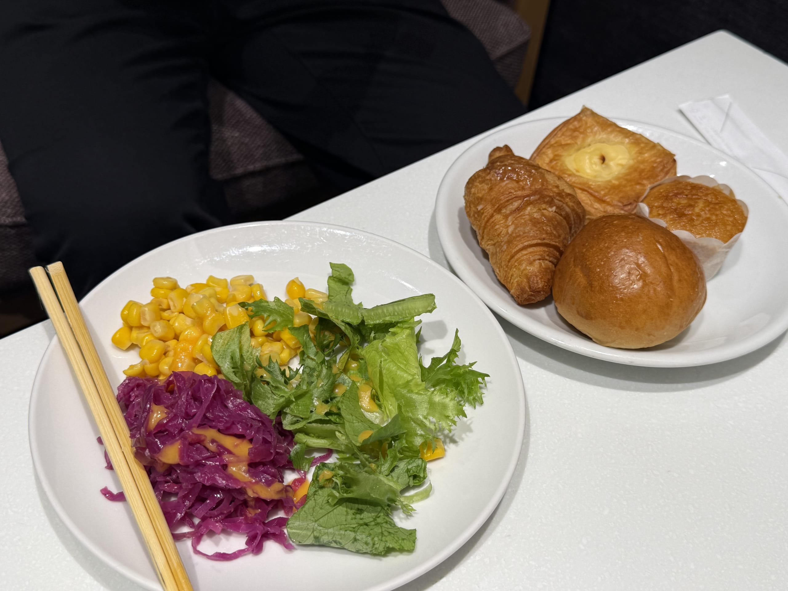 Salad, four pastries, and chopsticks on a table.