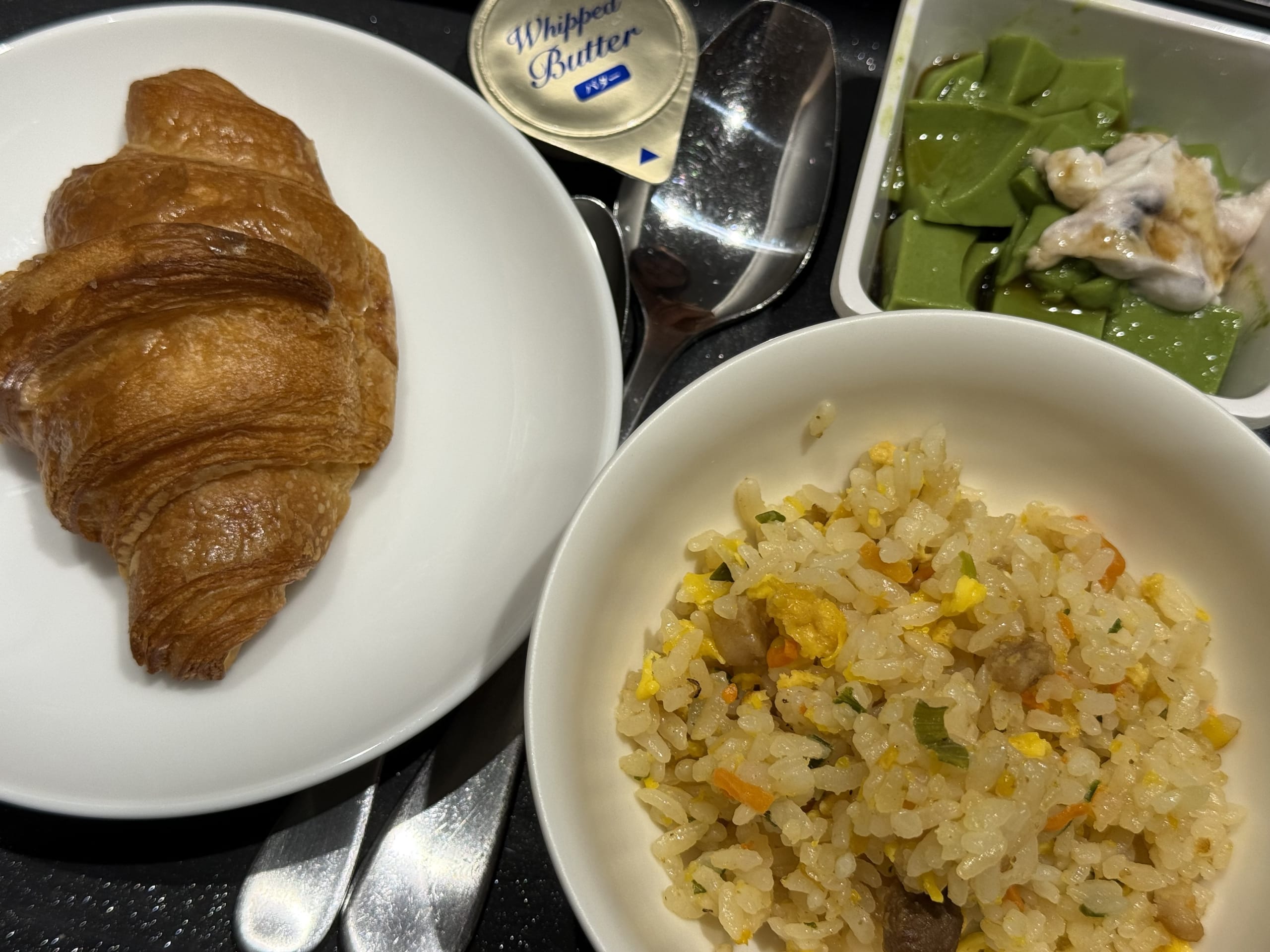 In-flight meal with a croissant and fried rice.
