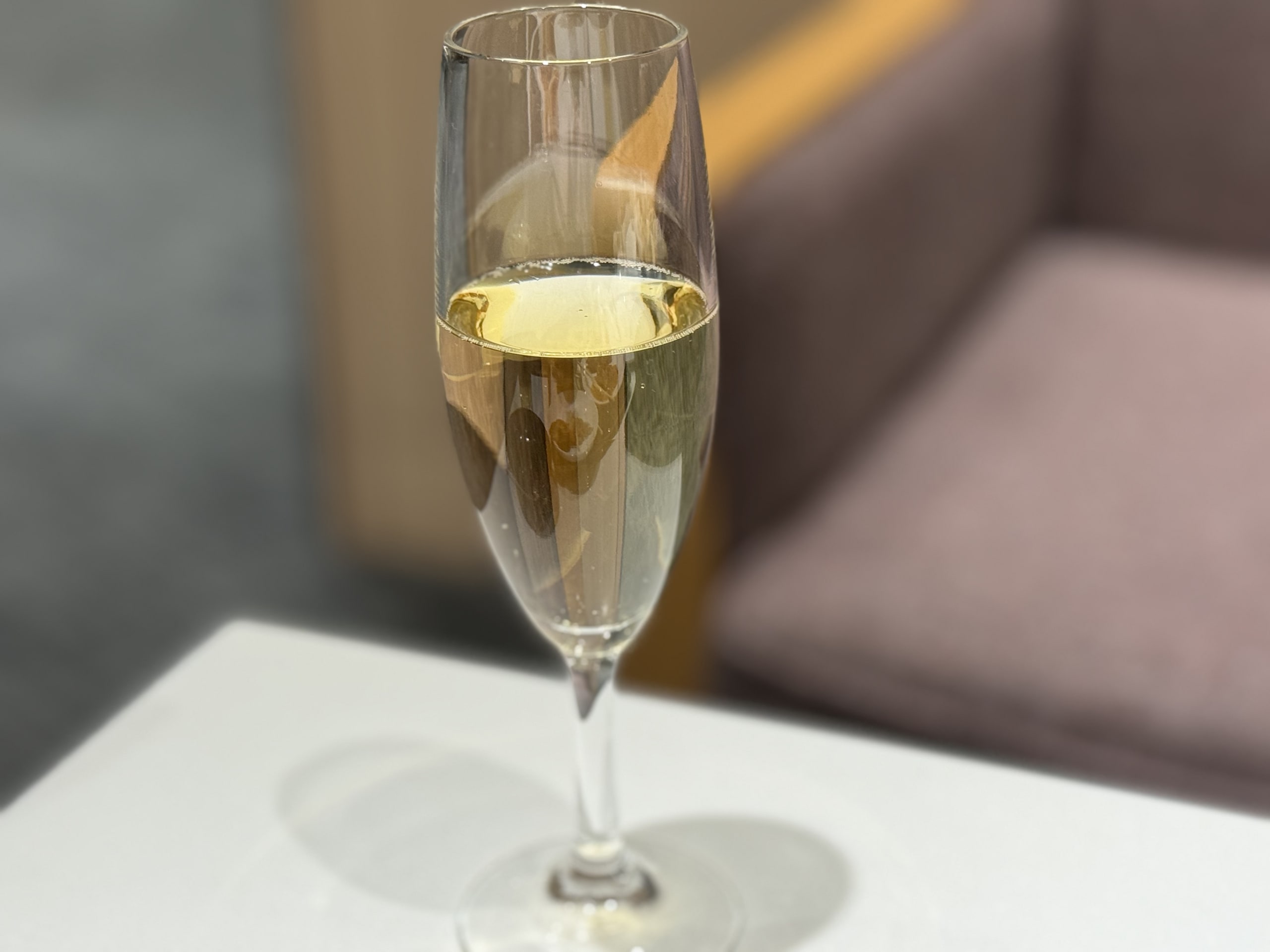 Champagne glass on a white table, brown sofa.