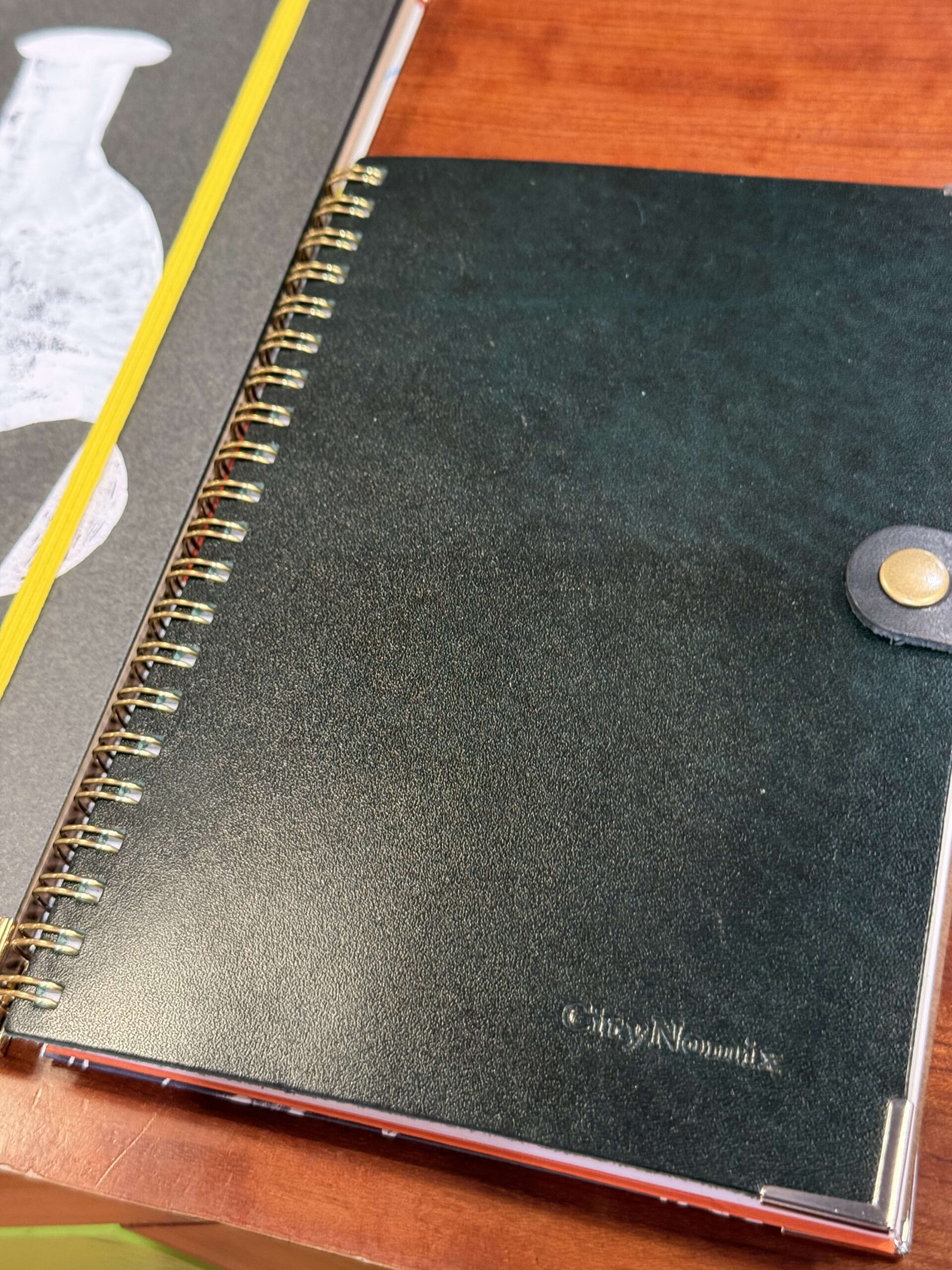 Green notebook with CityNomix logo on a wooden desk.