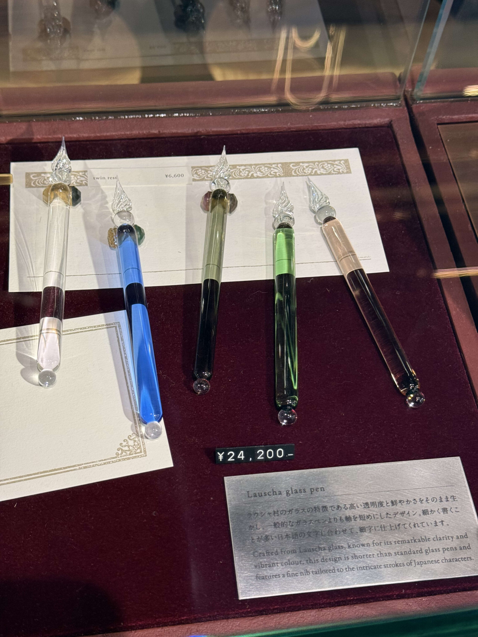 赤いベルベットに並ぶ5本のガラスペンと説明プレート。