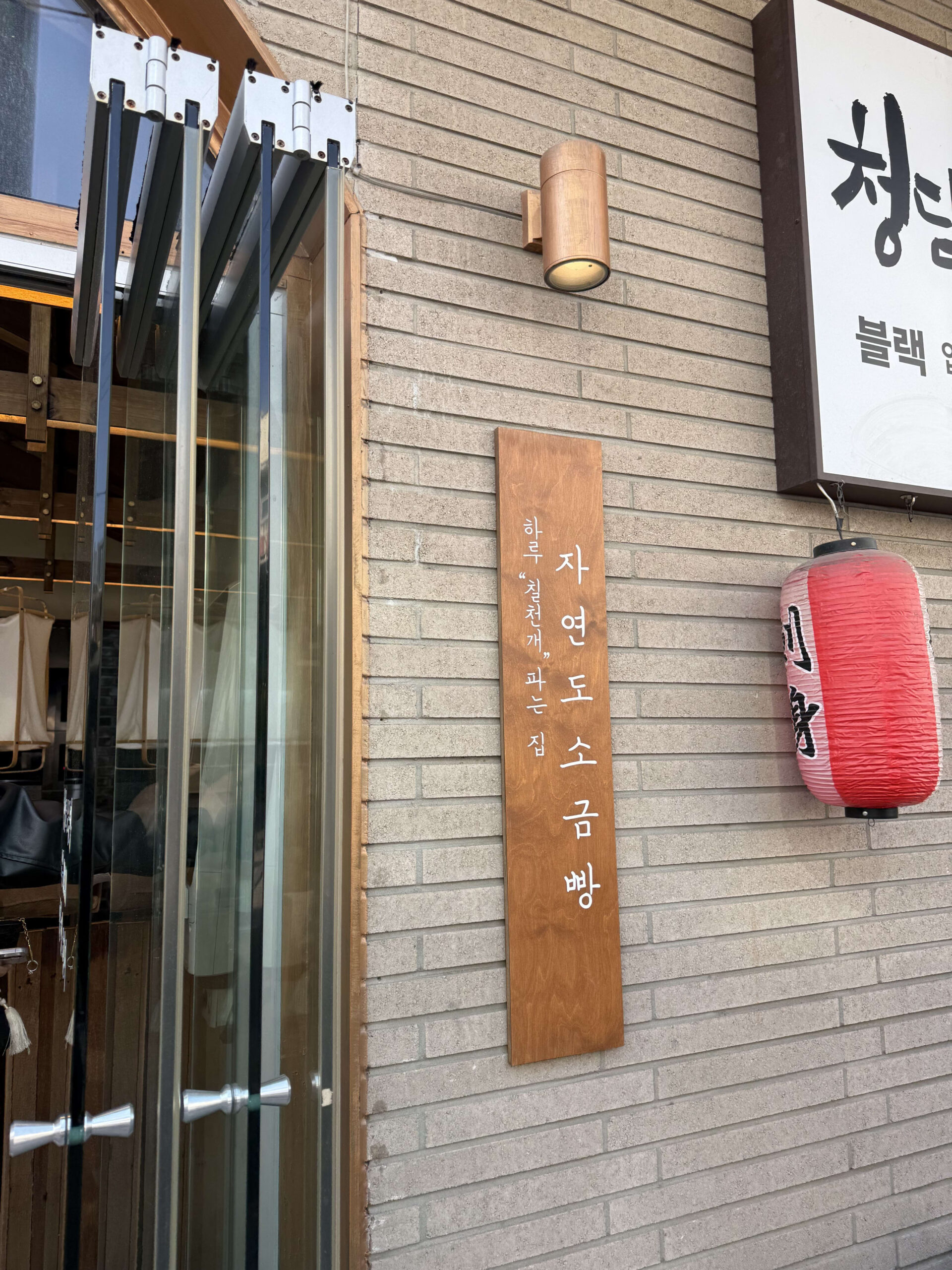 狎鴎亭のレンガ壁にある「自然島塩パン」の木製看板と外観。