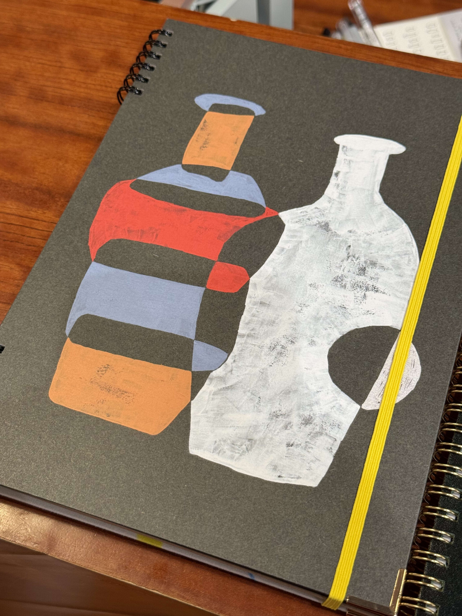 Acrylic painted bottles on a black notebook.