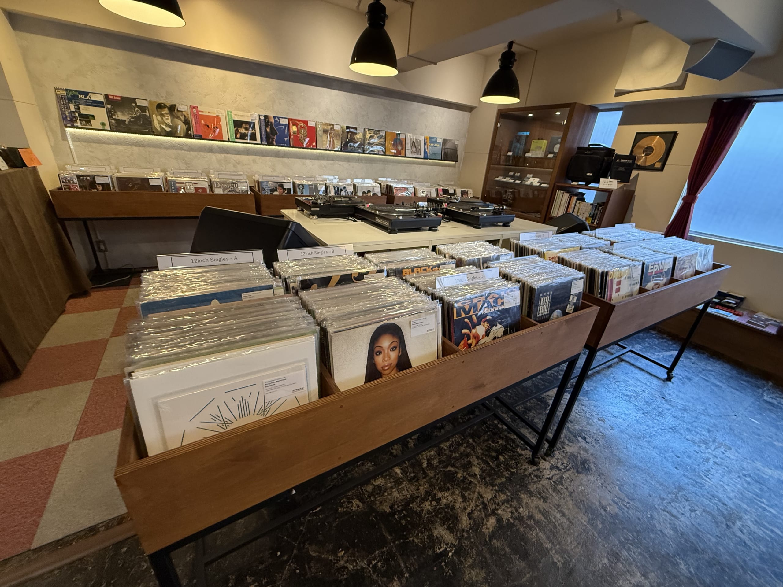 木製ラックに並ぶレコードと奥にターンテーブルが配置された店内。