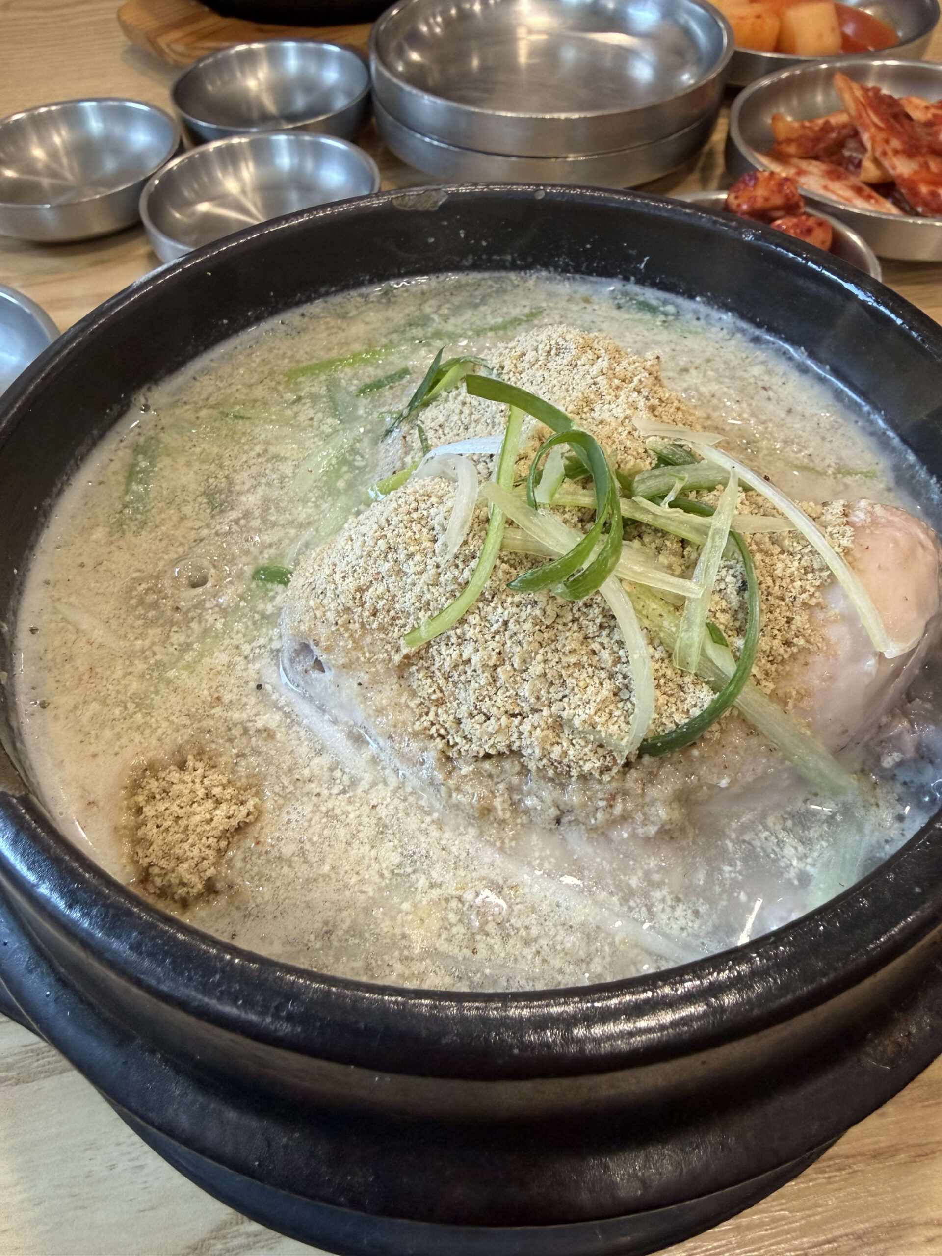 エゴマ粉とネギが乗った土鍋で煮立つ参鶏湯。