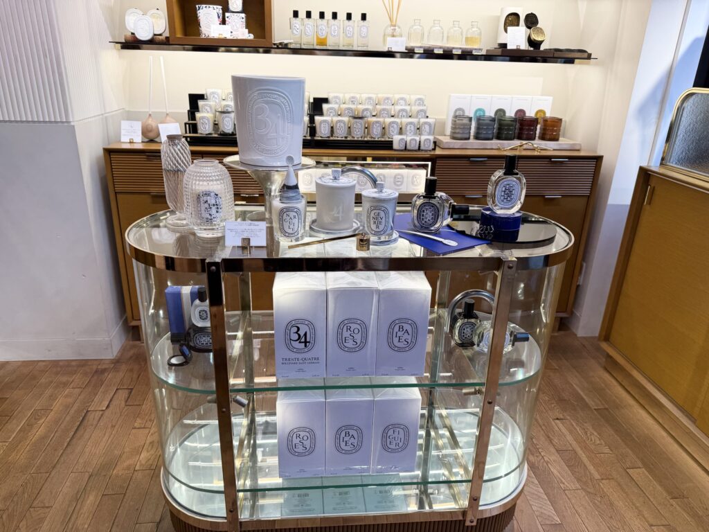 ディプティックのガラス製陳列棚に並ぶキャンドル、香水、34やROSESのロゴ入りギフトボックス