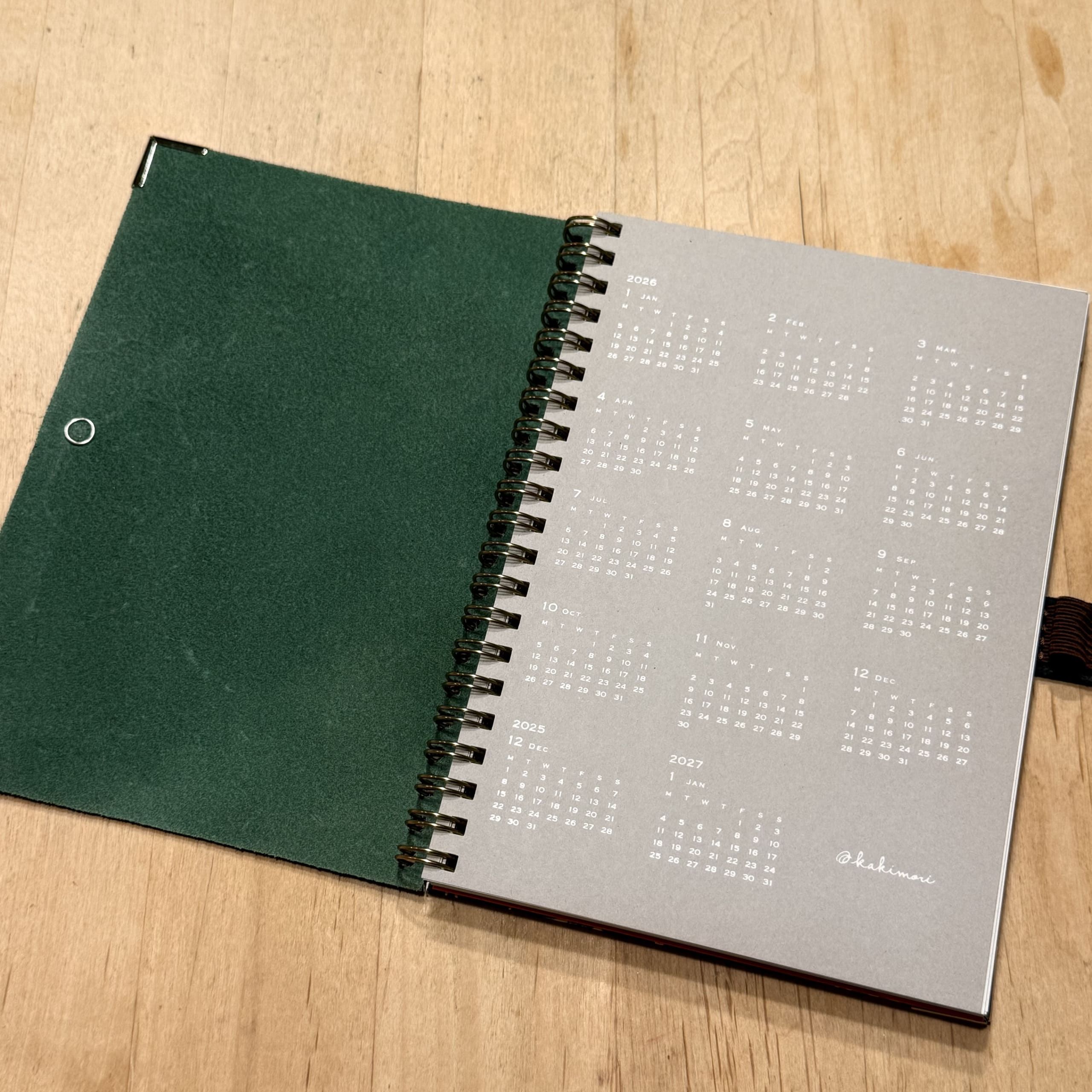 Open notebook on wood showing a 2026 calendar.