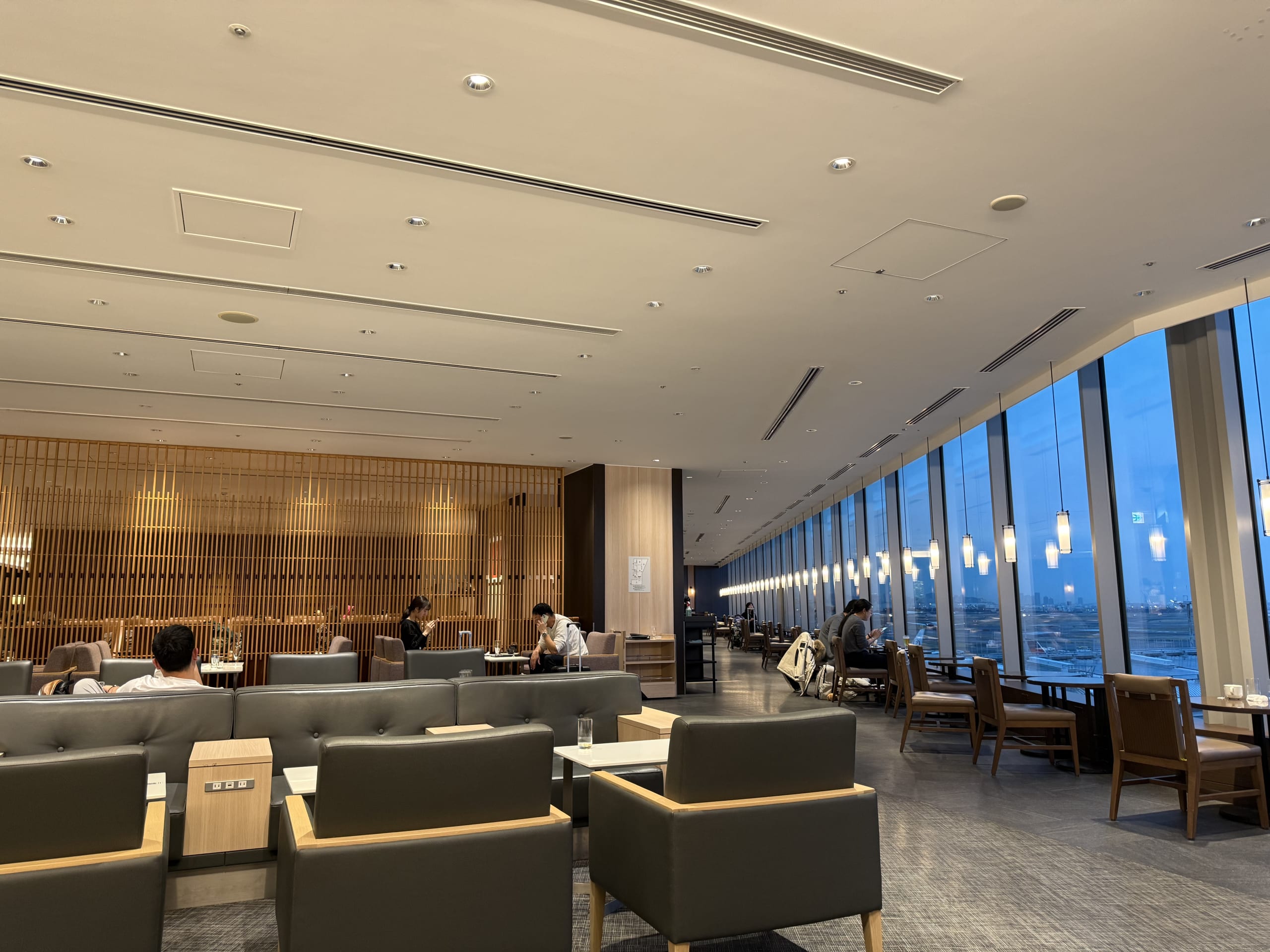 Airport lounge at dusk with people relaxing on sofas.