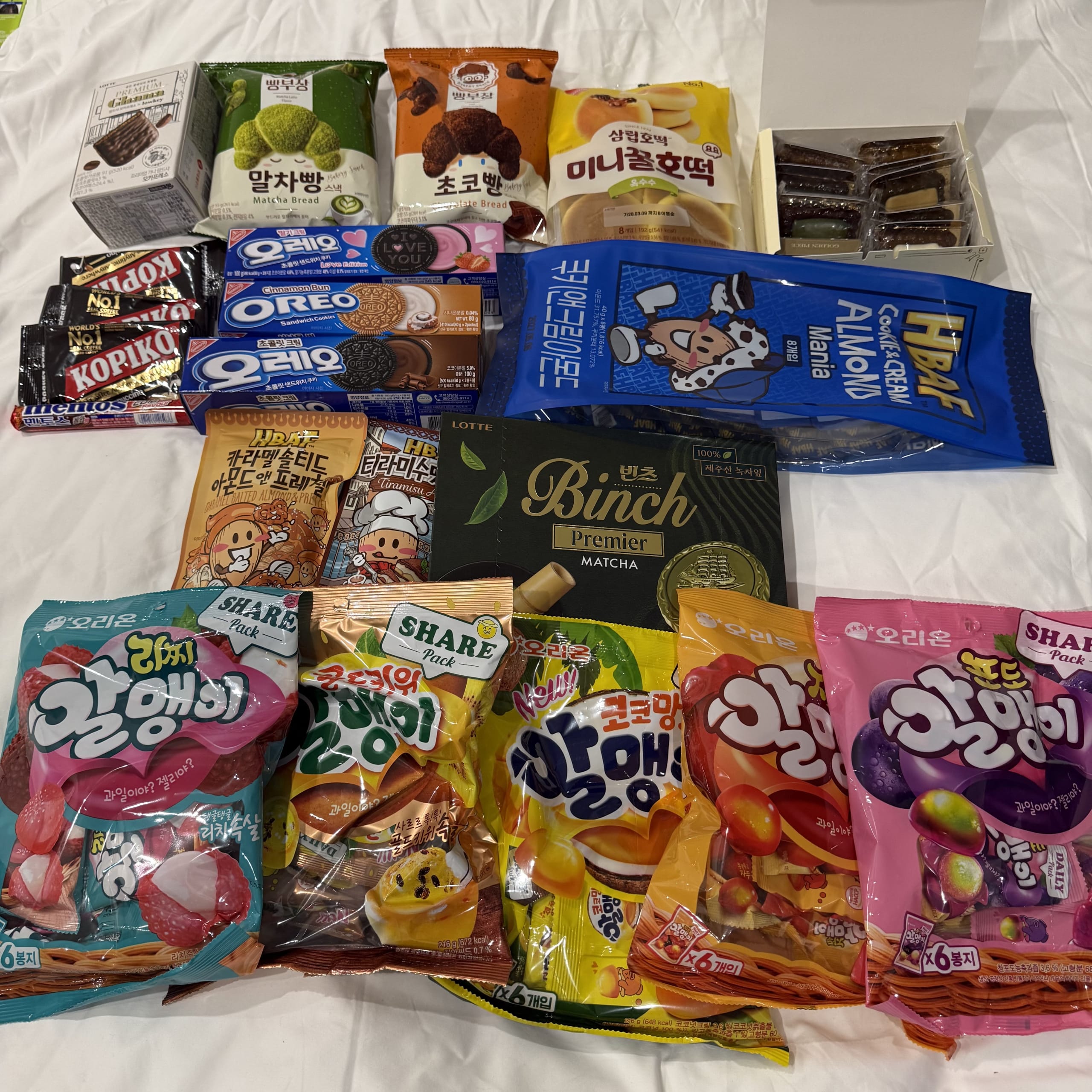 Various Korean snacks arranged on a white bed.