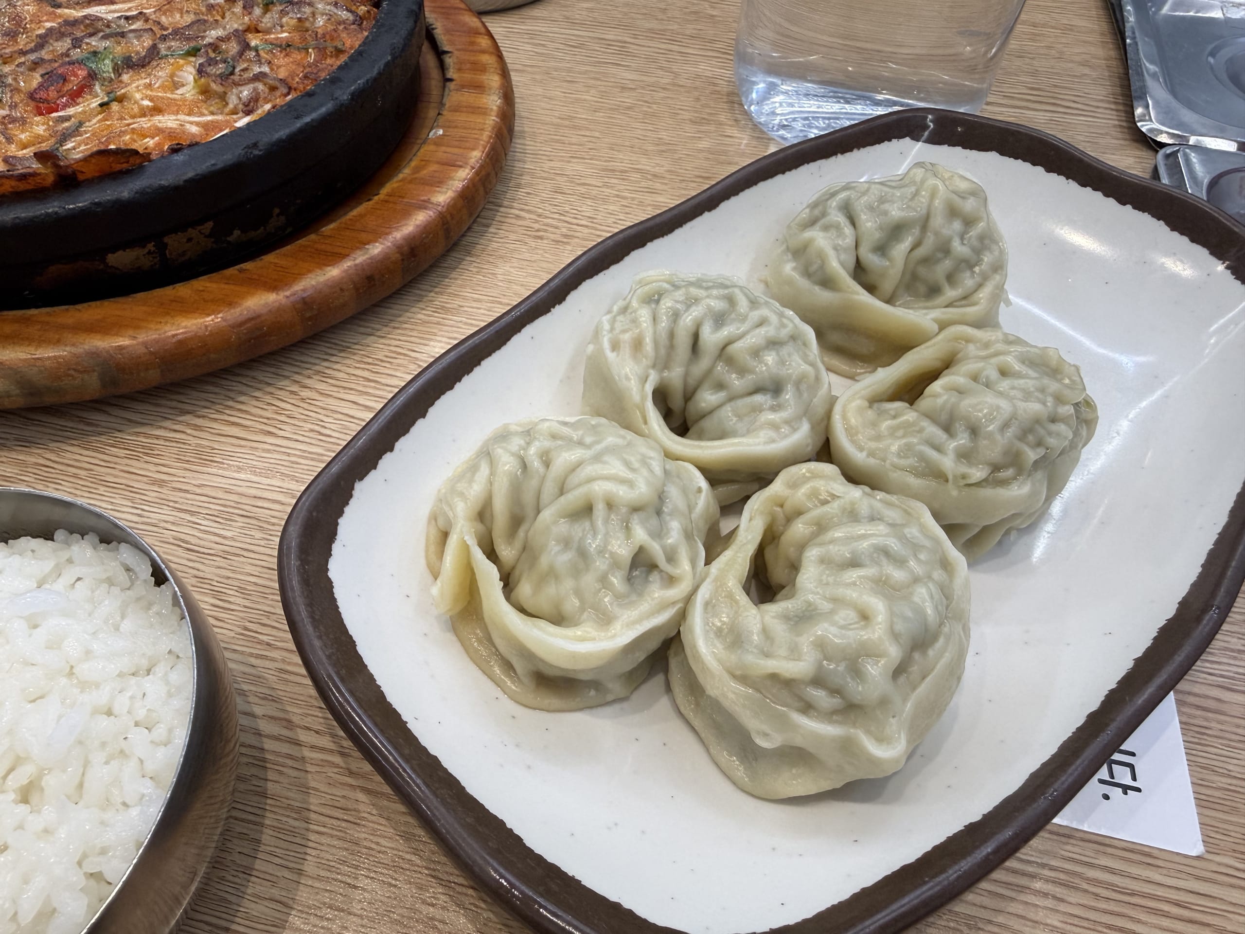 Five mandu, jeon, and rice on a table.