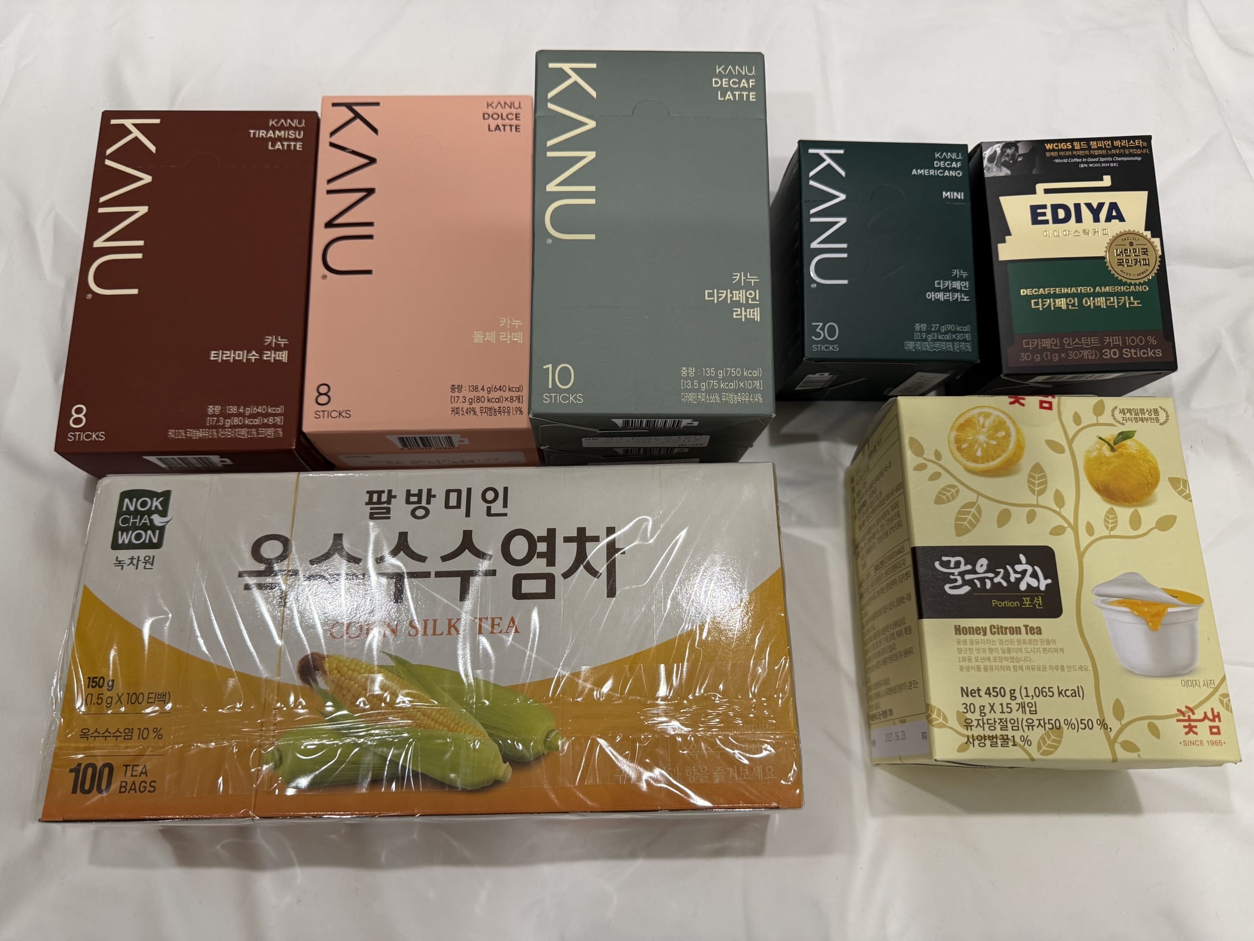 KANU coffee and corn silk tea boxes on a bed.
