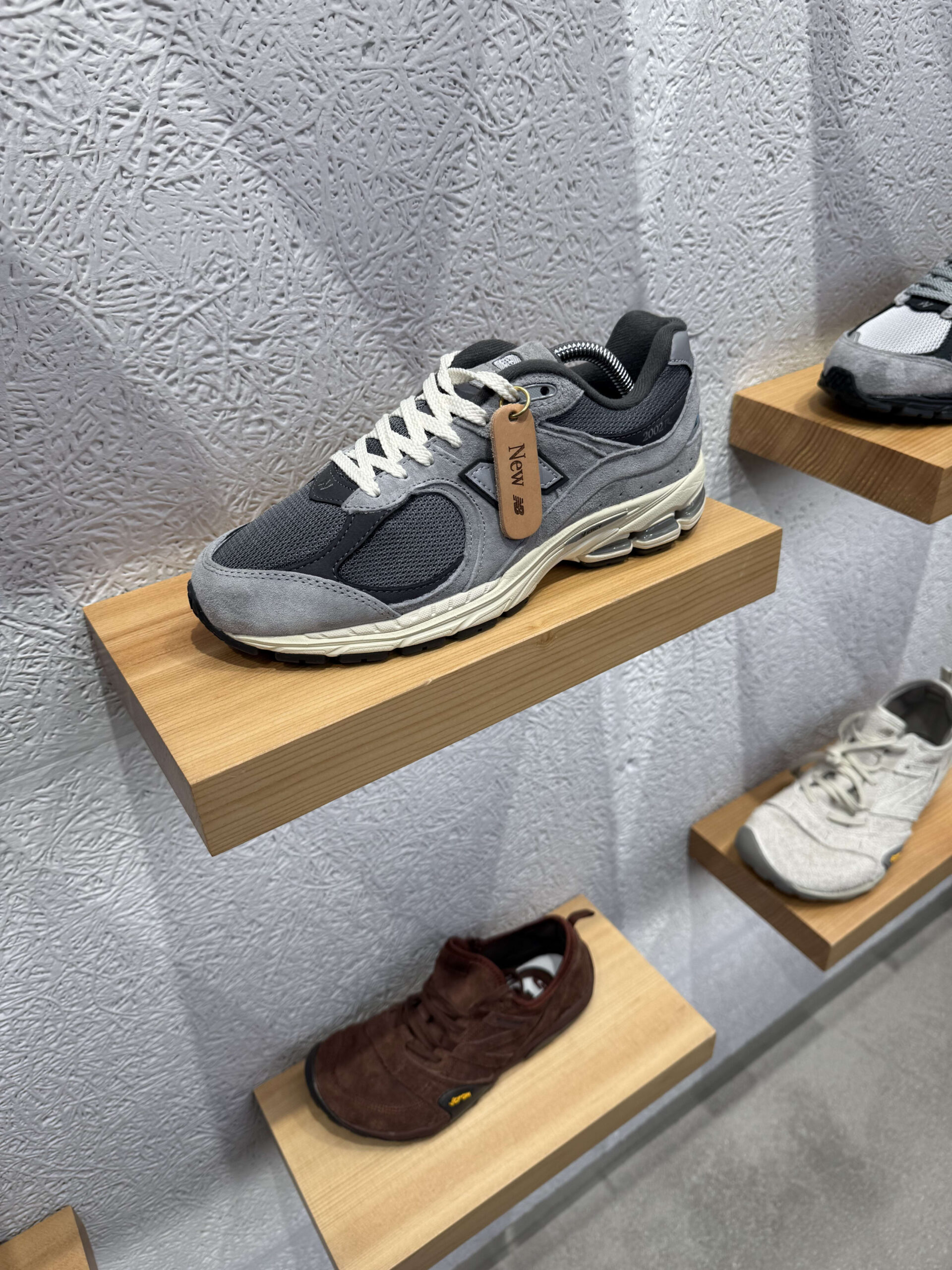 木製棚に展示されたグレーのニューバランス2002Rミュール。