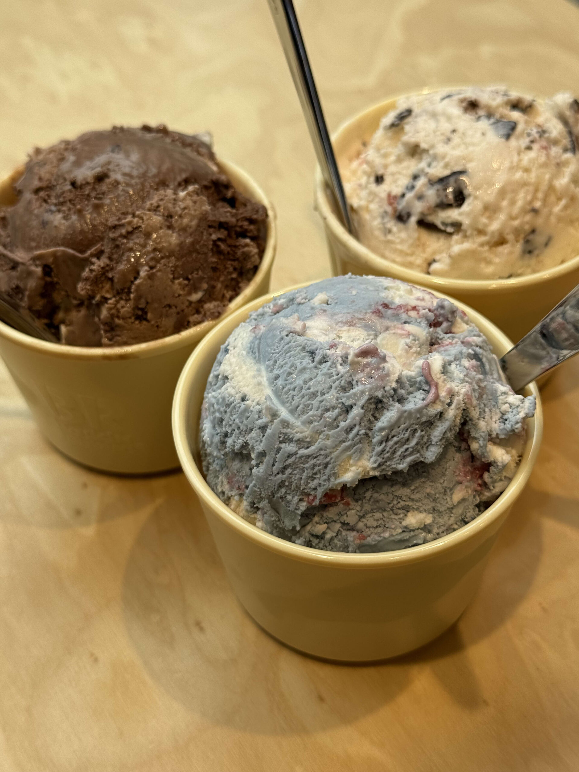 Three different ice cream cups on a wooden table.