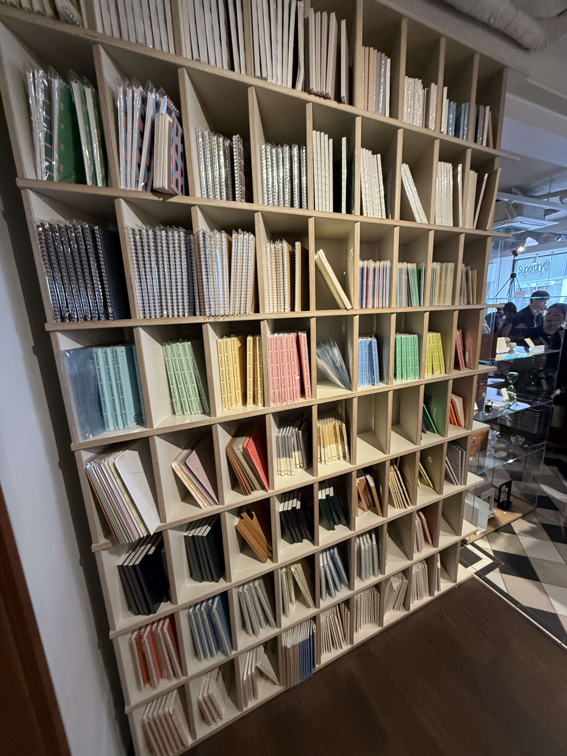 A wooden shelf full of colorful notebooks.