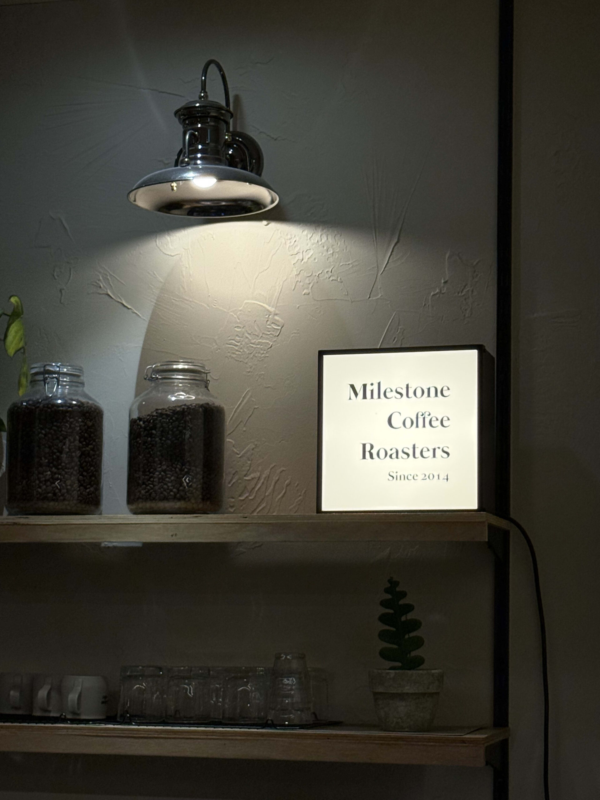 Jars of coffee beans and a Milestone Coffee sign.