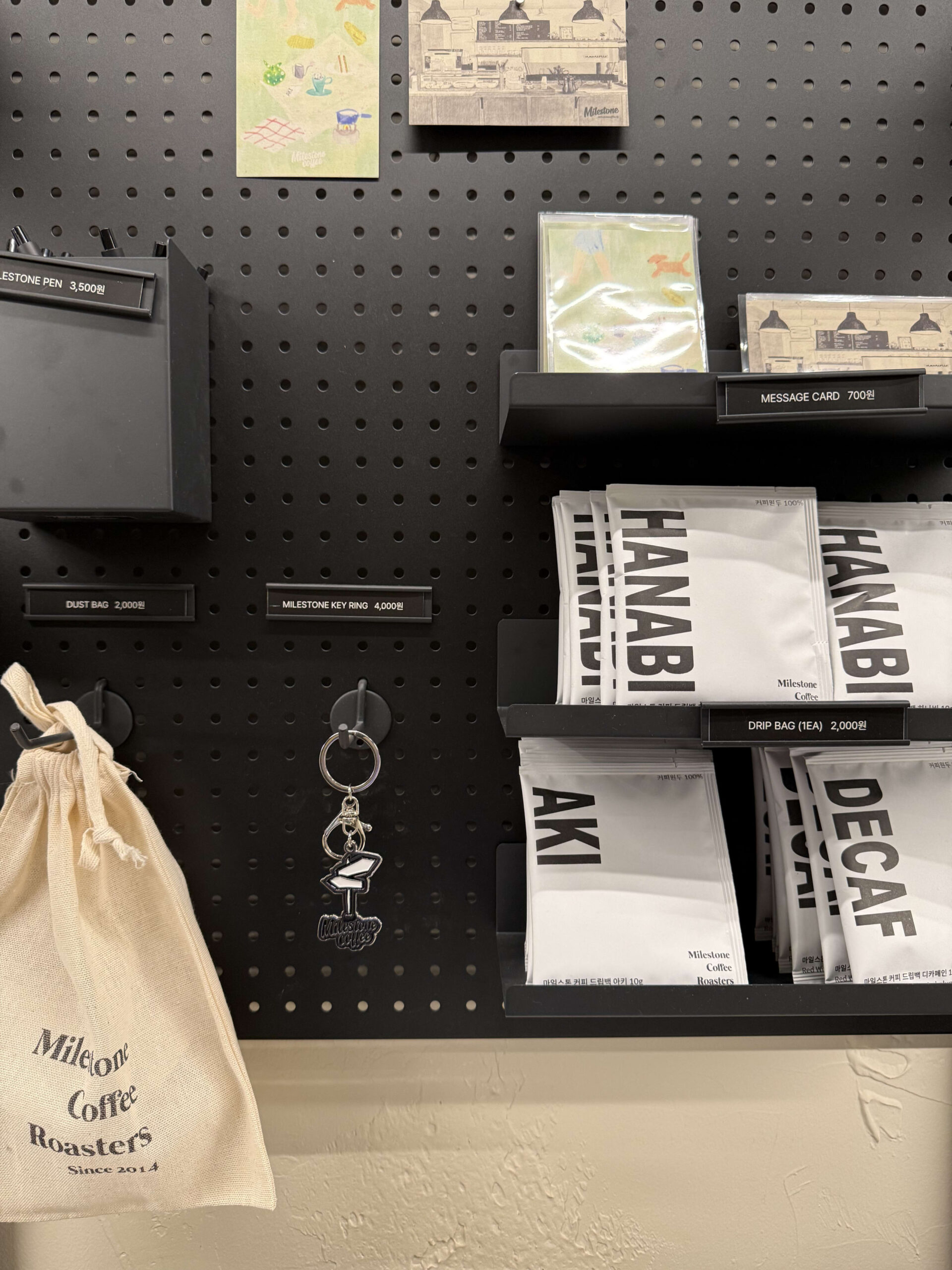Milestone coffee goods on a black pegboard.