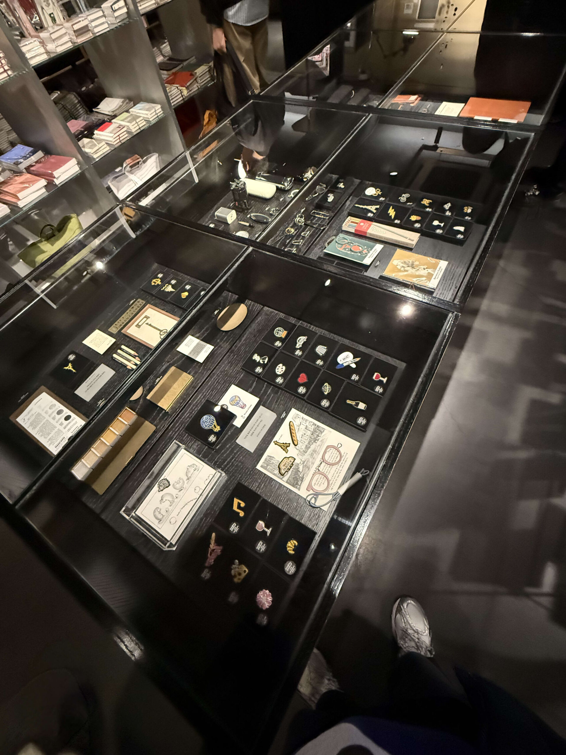 Pins and stationery displayed in a black glass showcase.