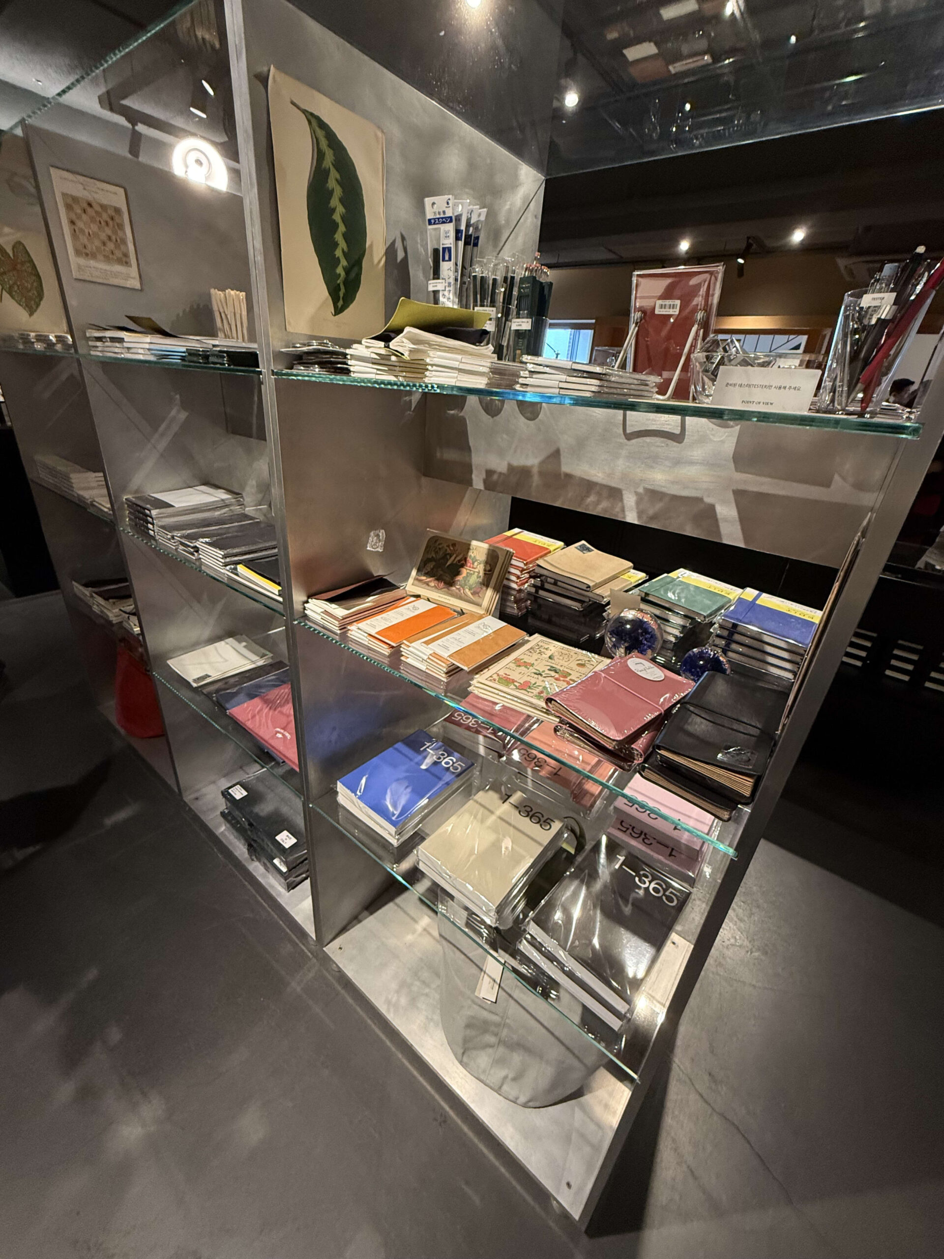 Stationery displayed on glass and steel shelves.
