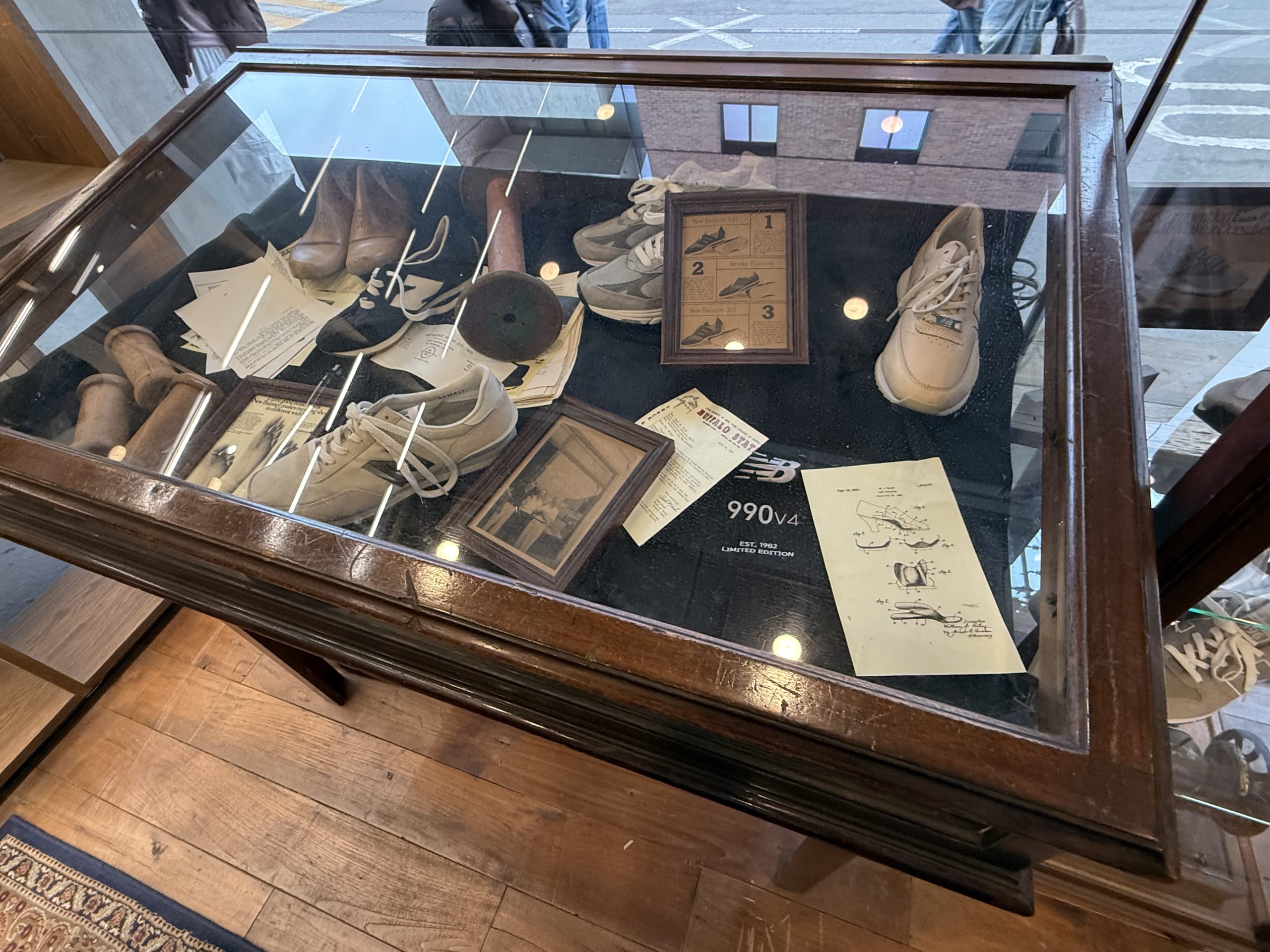 ニューバランス聖水店1階の木製ケース。古いスニーカーや設計図の展示。