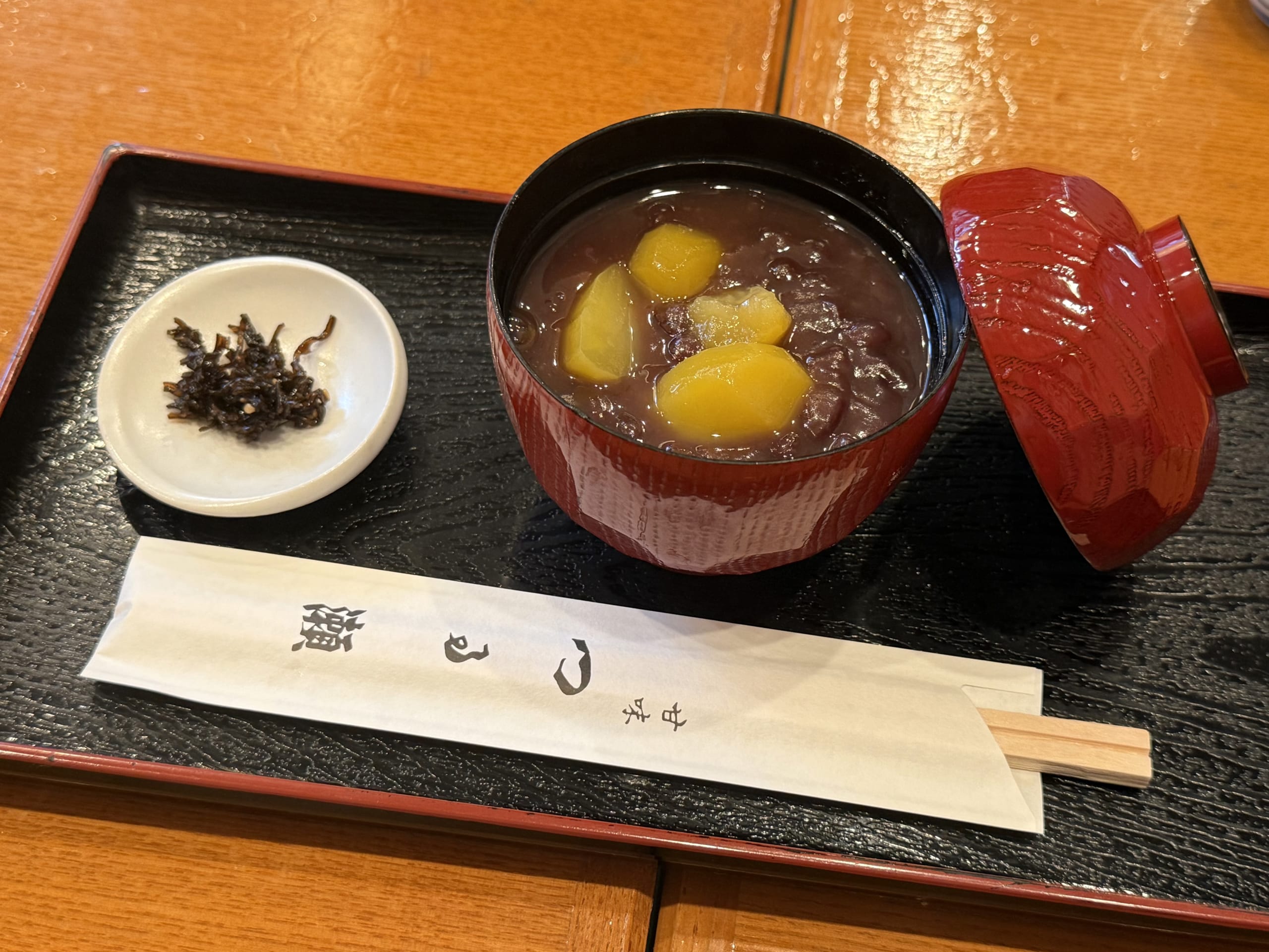 黒盆に乗った栗ぜんざいと塩昆布、つる瀬の箸袋。